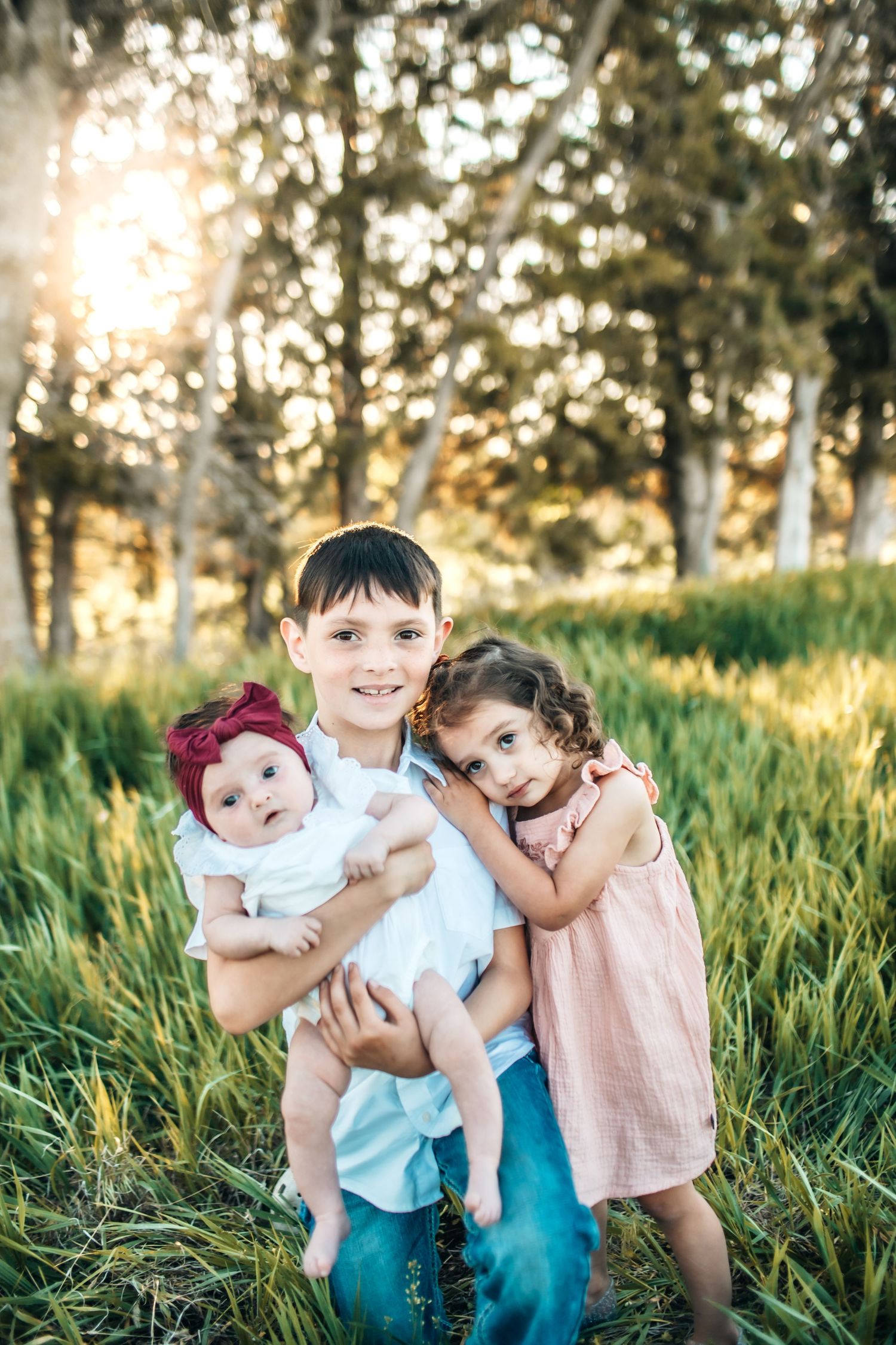 Children posed together in sunlit grassy field.
