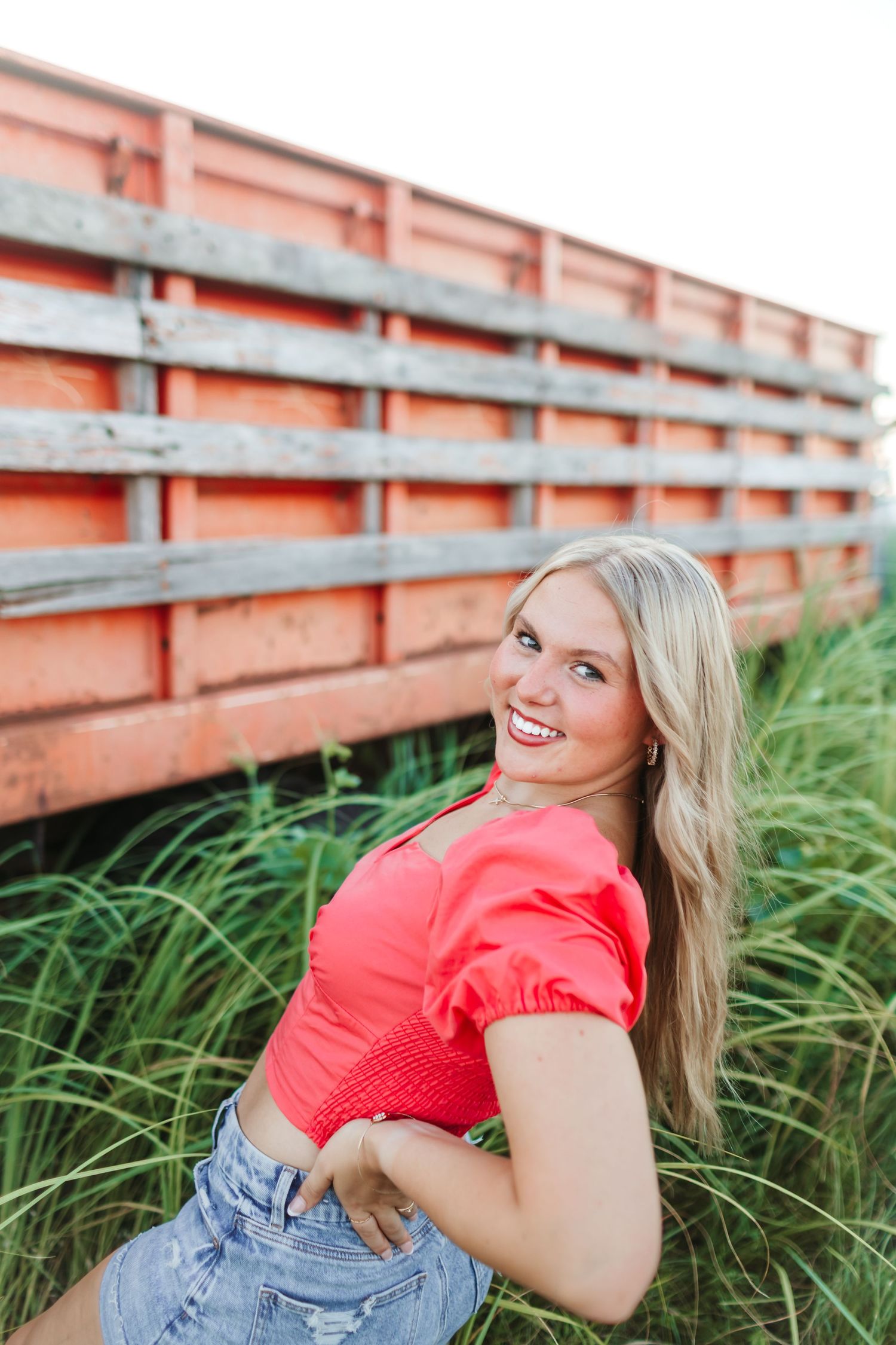 Fun outdoor portrait session with pink top and denim shorts near old farm truck.