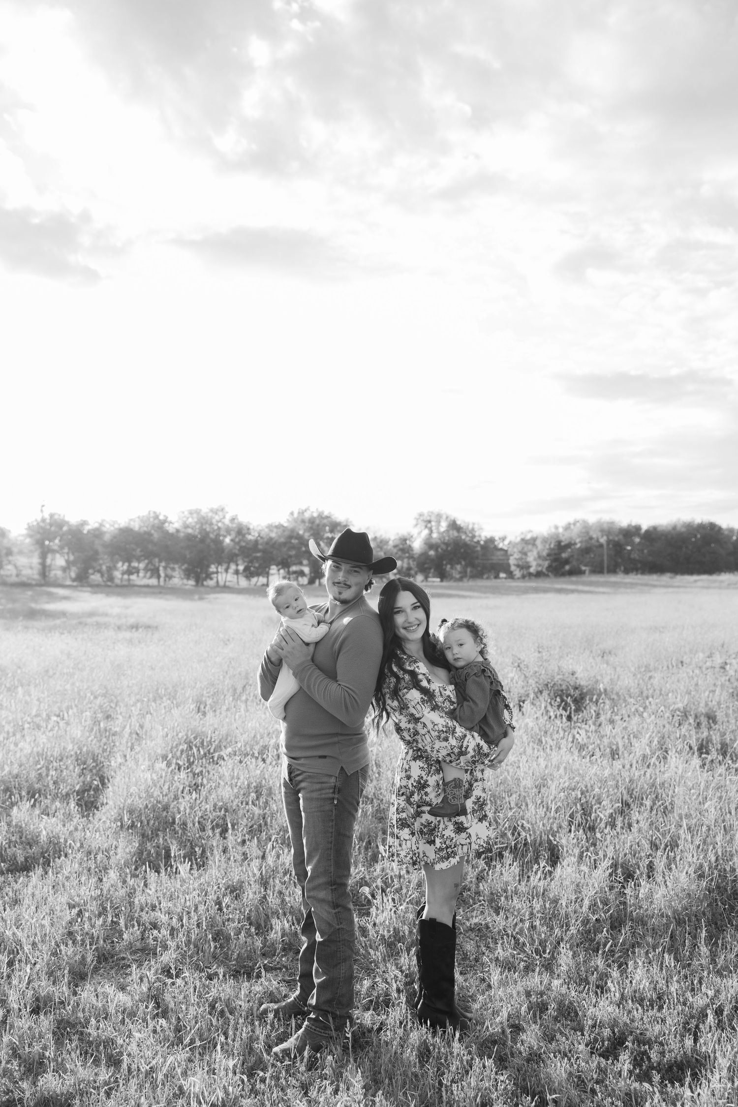 Family group posing together in a scenic field during golden hour.