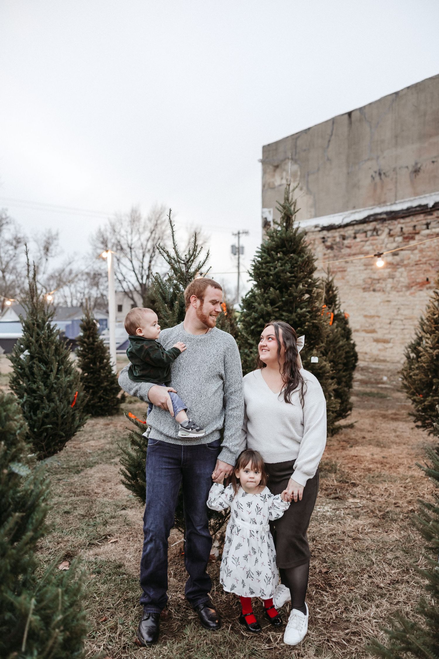 Candid family photo session among evergreen trees.