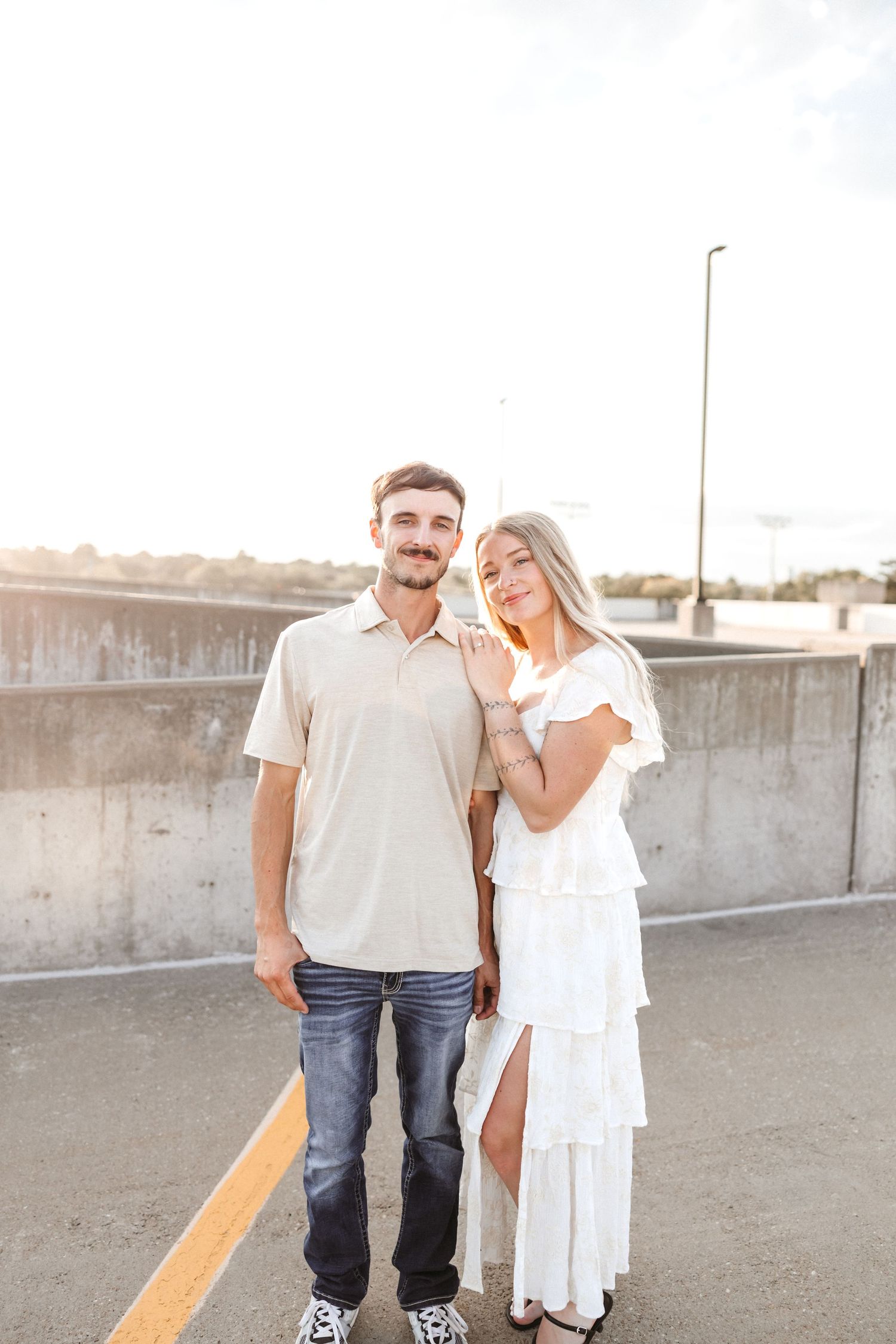A couple poses together on a concrete rooftop during golden hour.