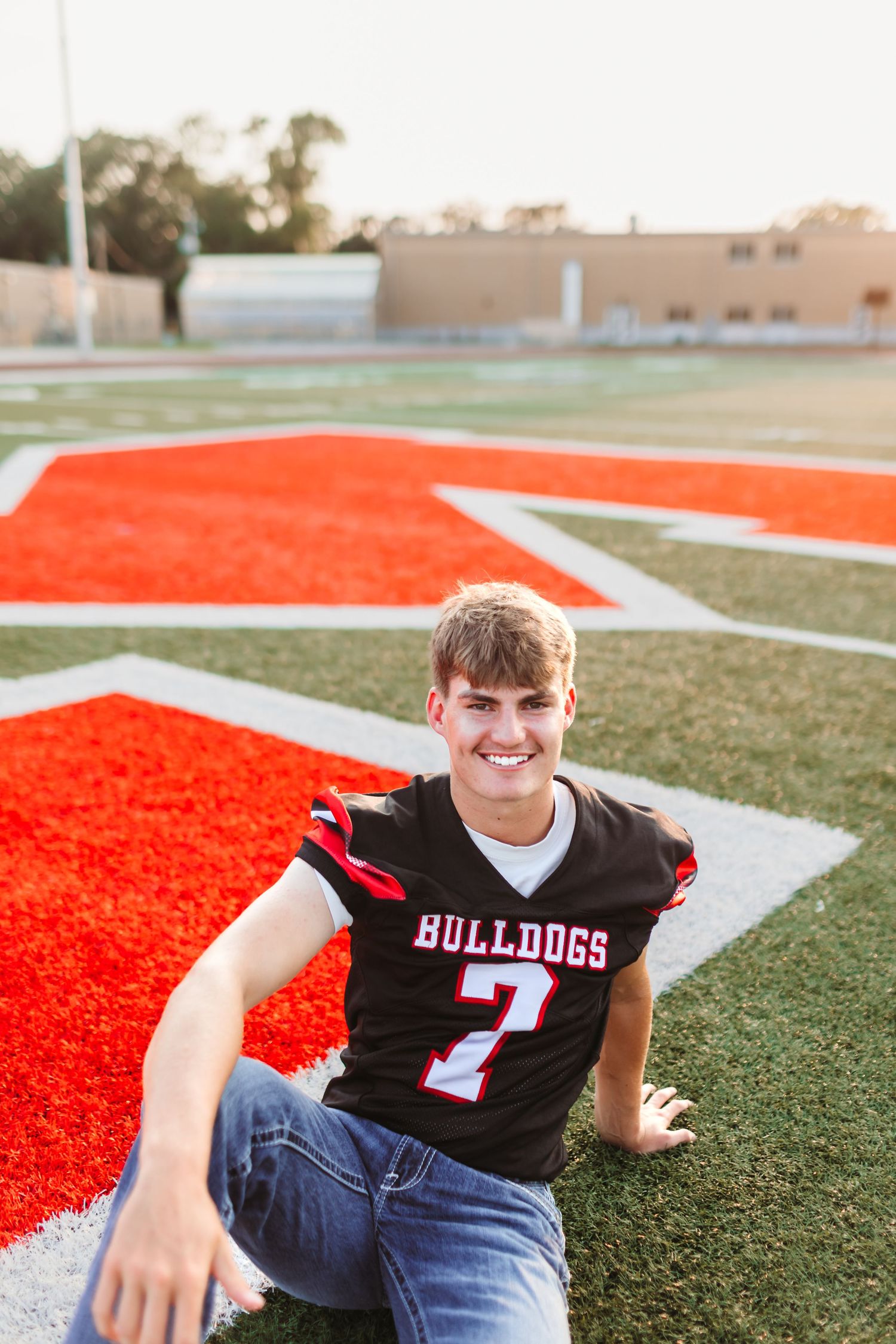 Football player in Bulldogs jersey number 7 posing on red field turf.
