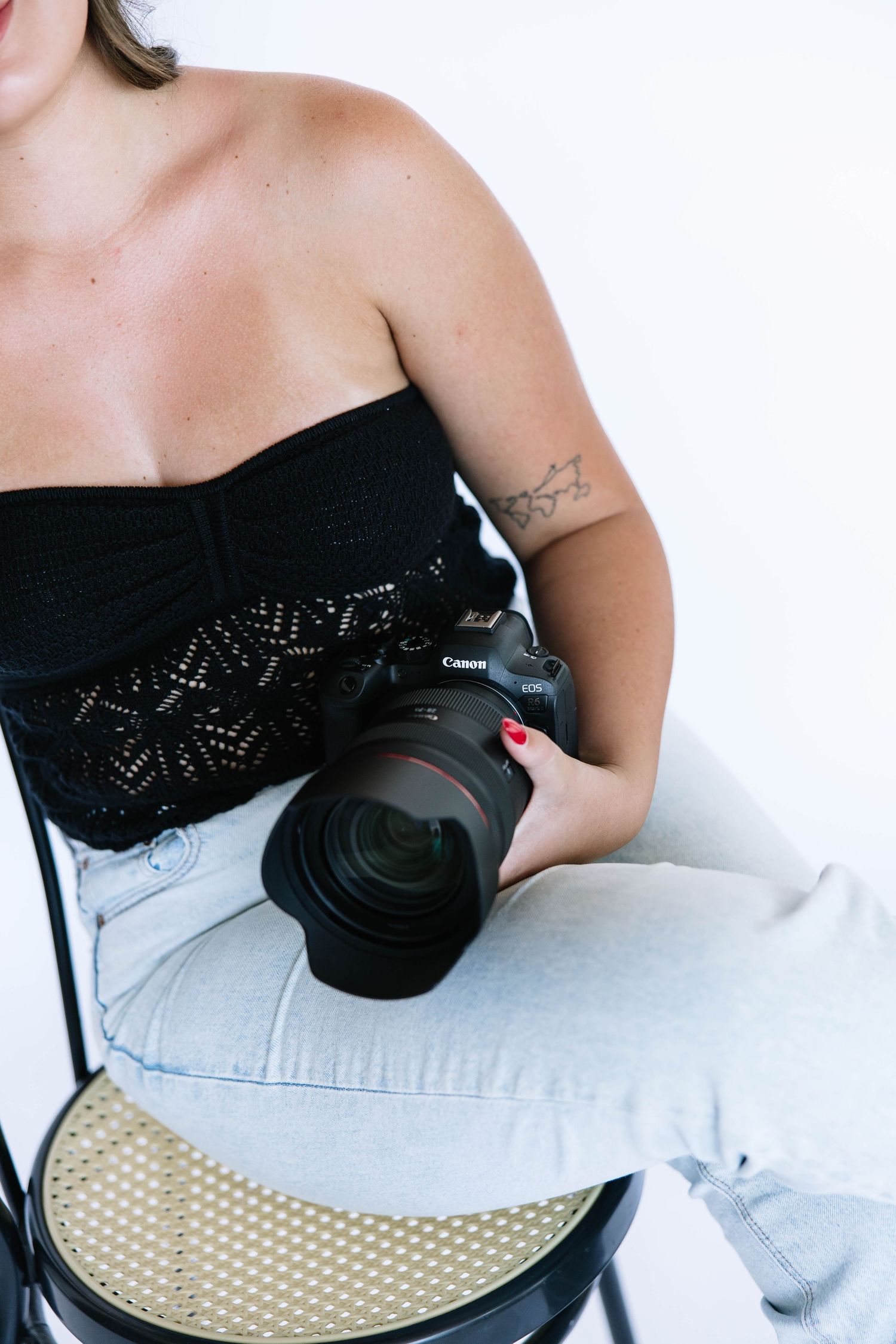 Professional camera and black lace shirt against white studio backdrop.