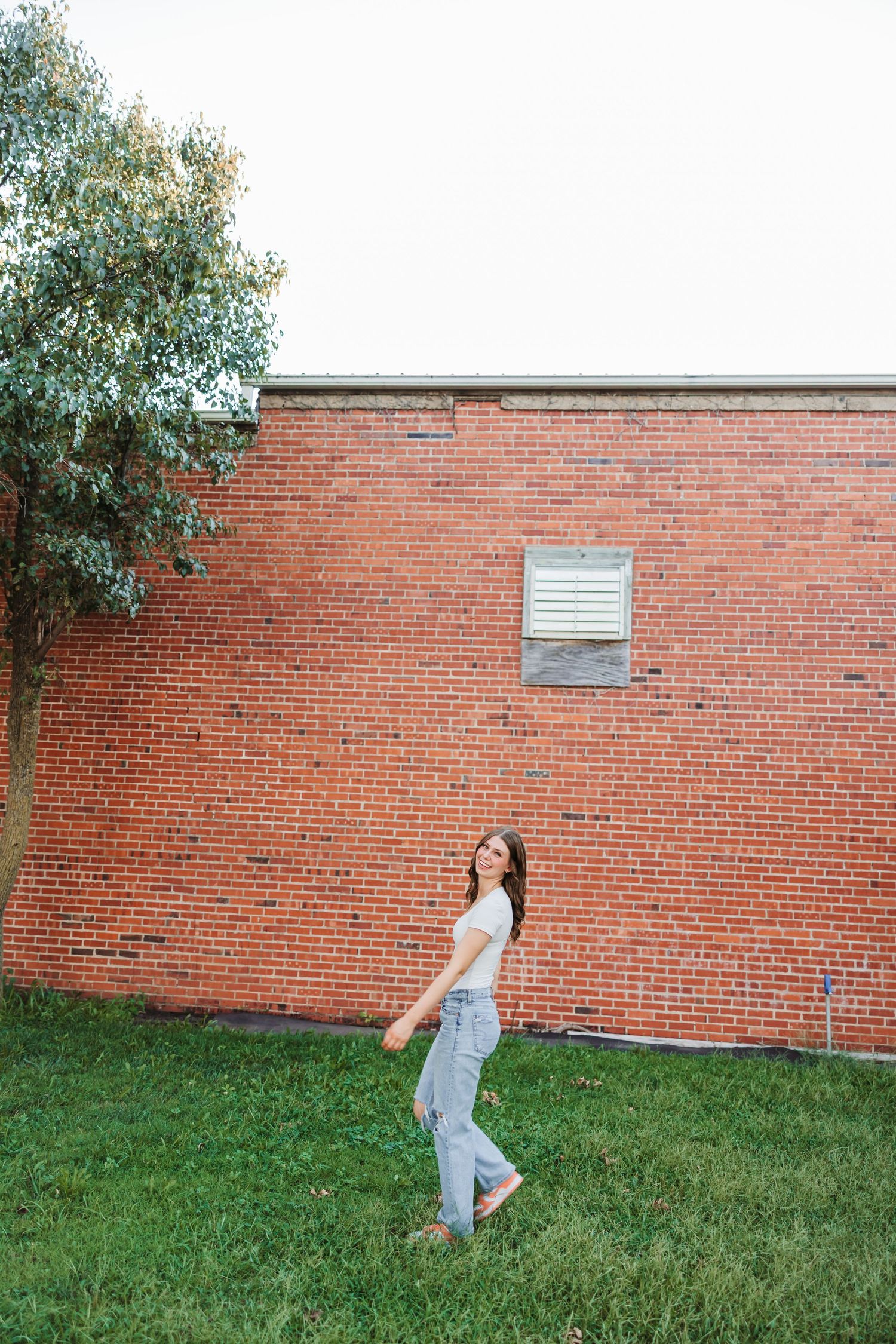 Energetic poses against a red brick wall on a grassy lawn.