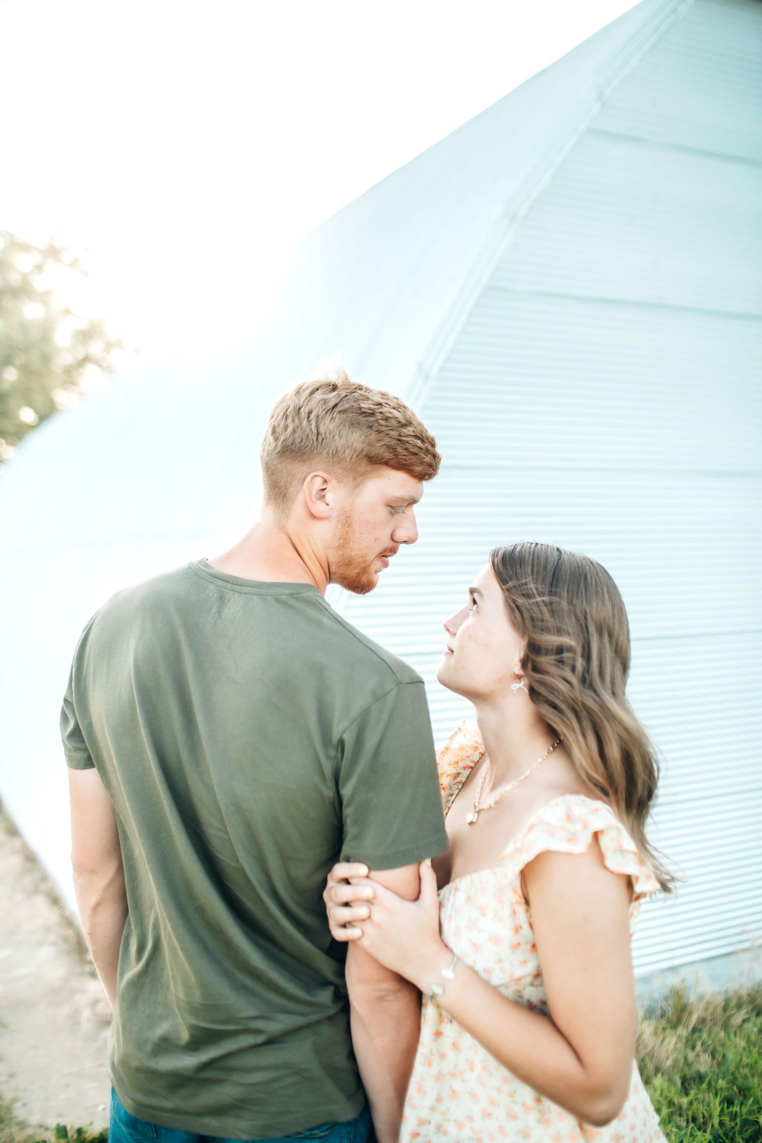Couple in casual attire sharing a romantic moment against an old building.