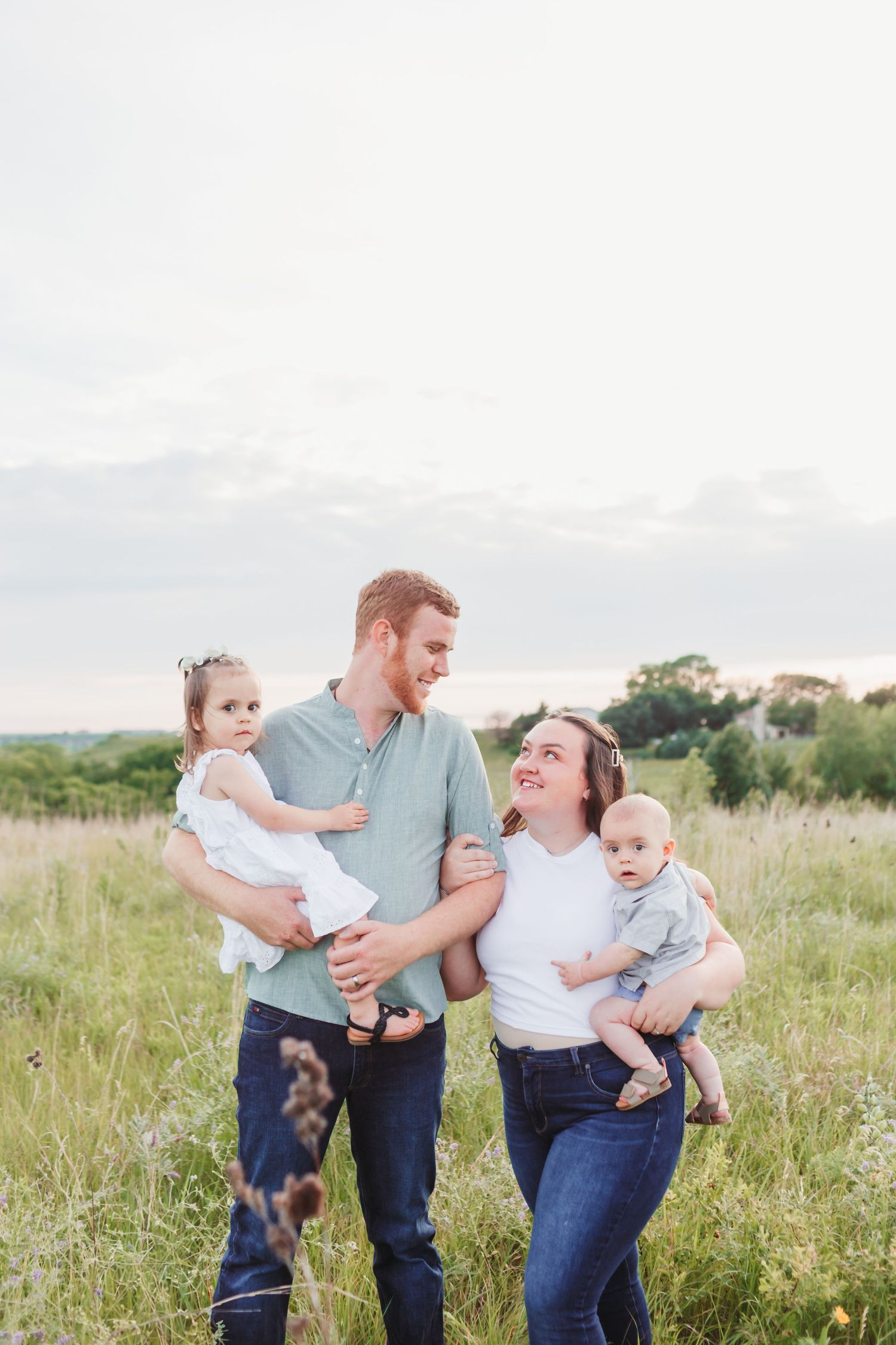 A playful family enjoying quality time together in a grassy field during golden hour.