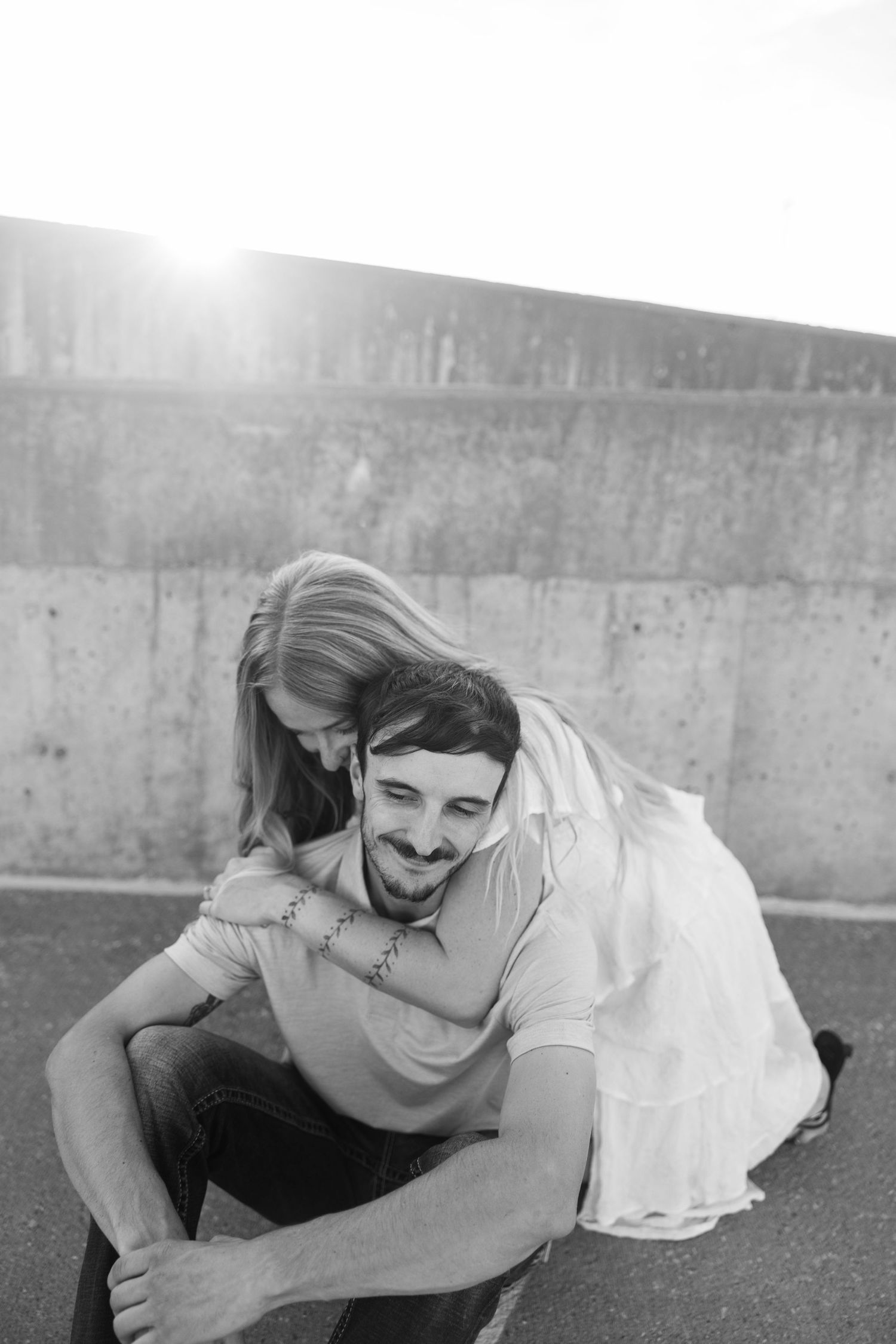 Playful couple lying down and laughing together in black and white photography.