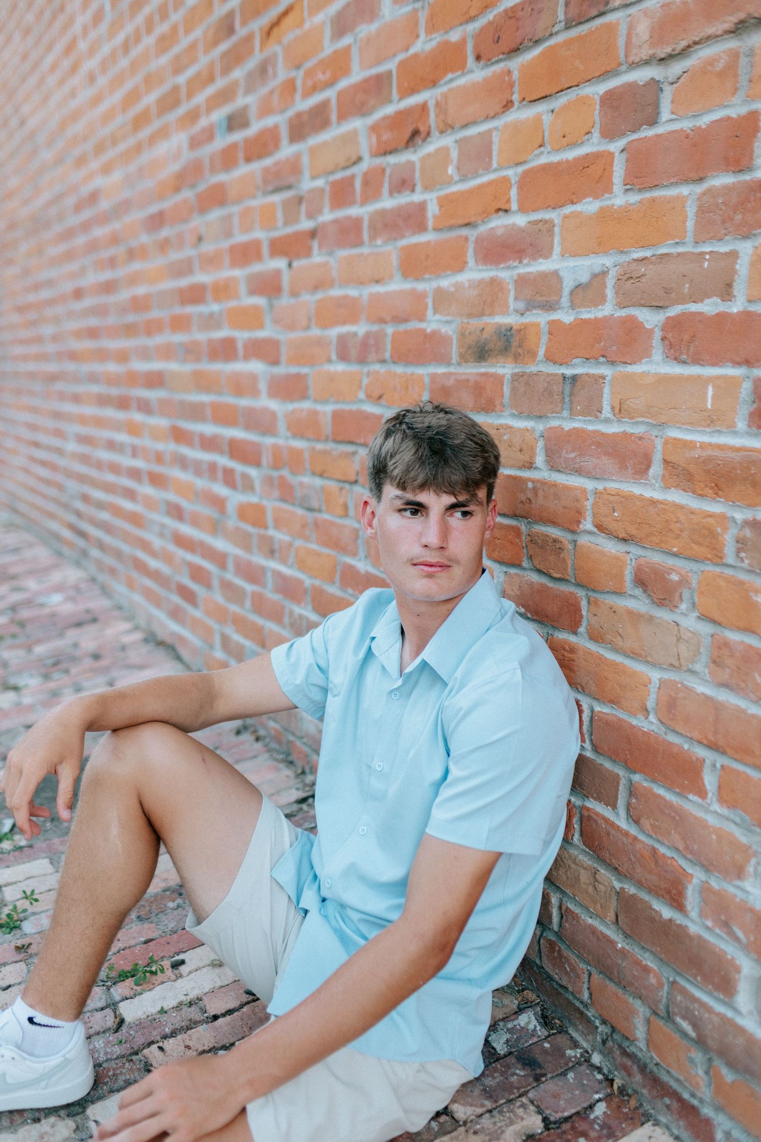 Summer portrait against textured brick wall in casual blue attire.