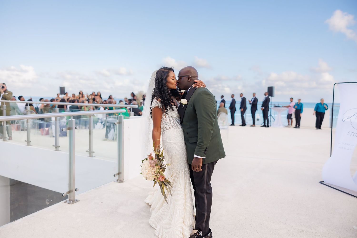 Luxury wedding picture of Bride and groom share a kiss on a rooftop overlooking the ocean after ceremony.