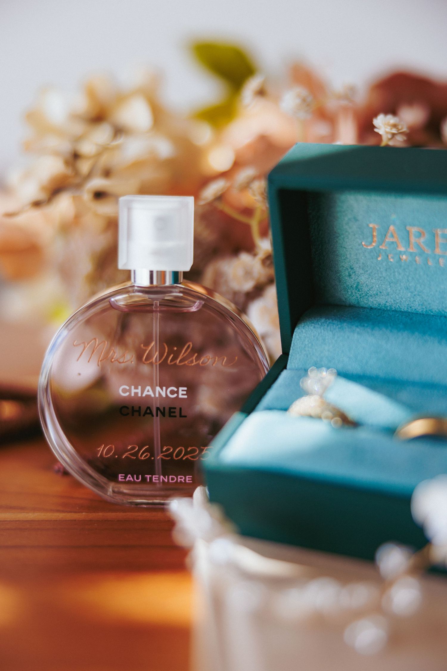 Luxury wedding picture of Chanel Chance Eau Tendre perfume customized for Mrs. Wilson beside teal Jared jewelry box with rings.