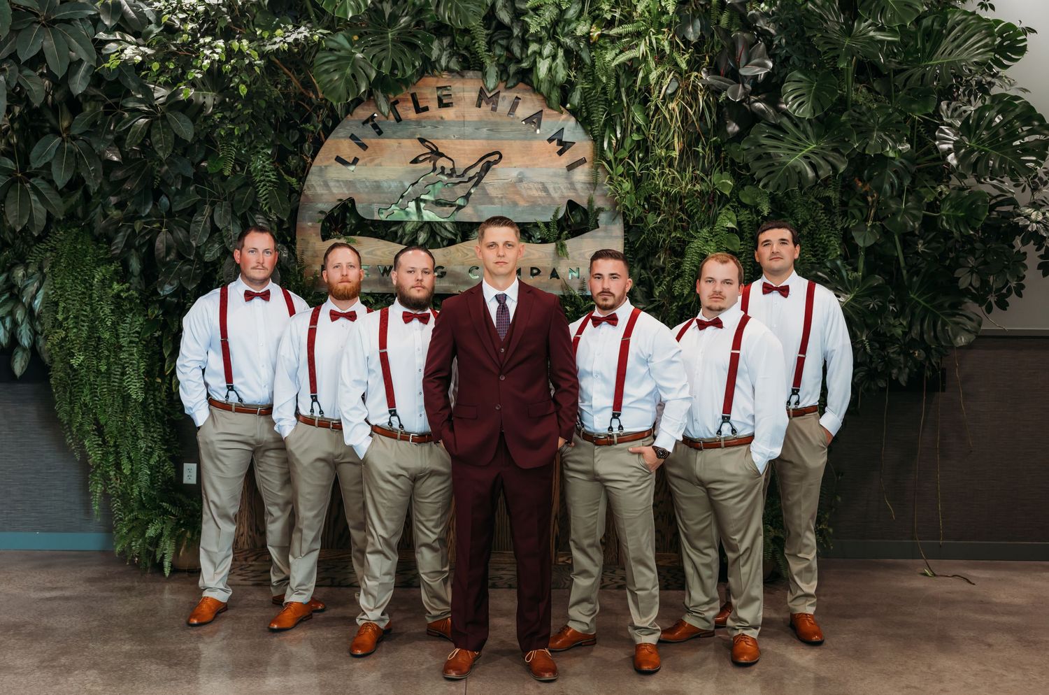 Luxury wedding picture Groom in burgundy suit poses with groomsmen in suspenders at Little Miami wedding venue.