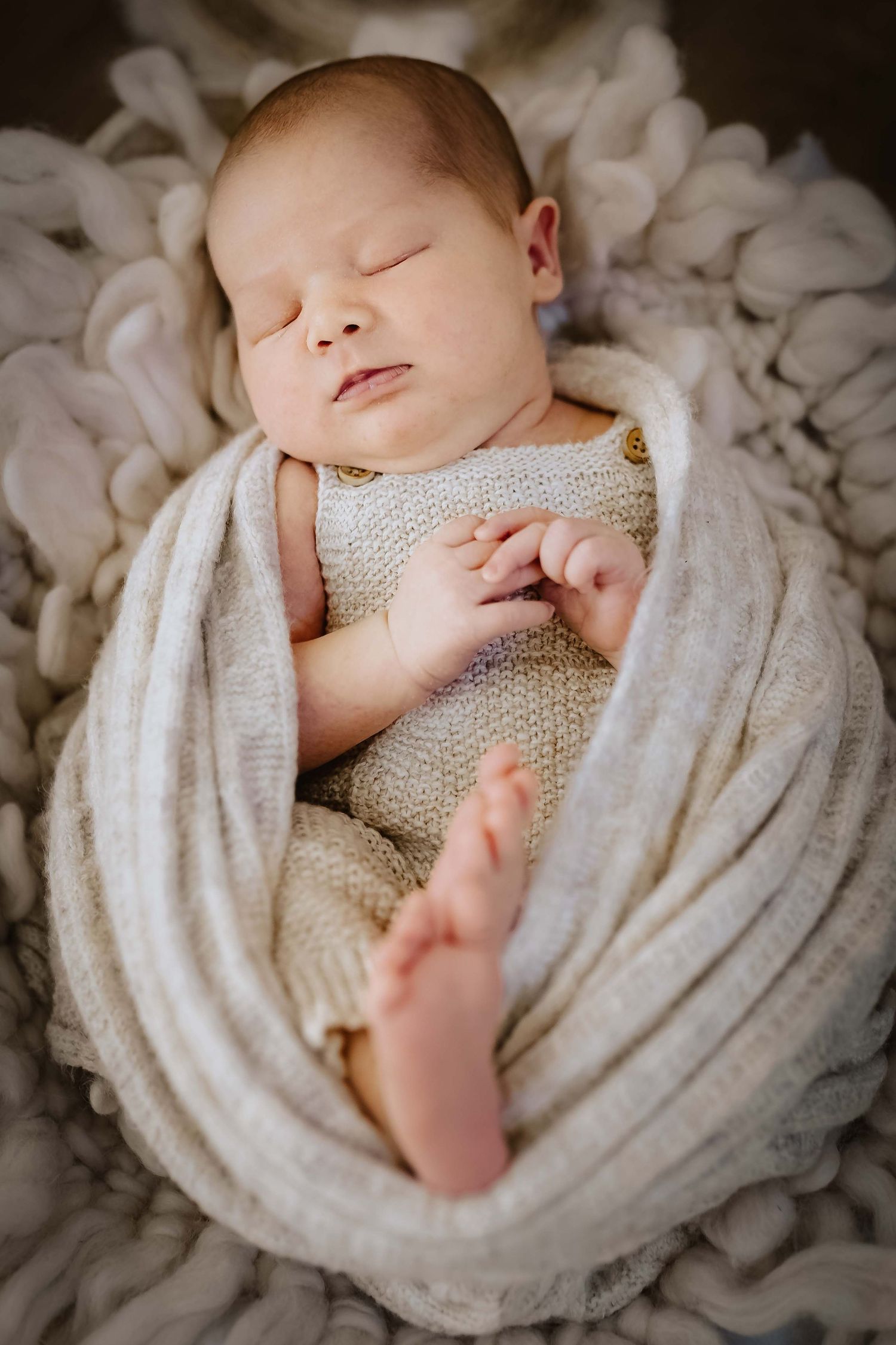 Baby schläft im Korb eingewickelt in einen wrap, natürlich im Studio fotografiert