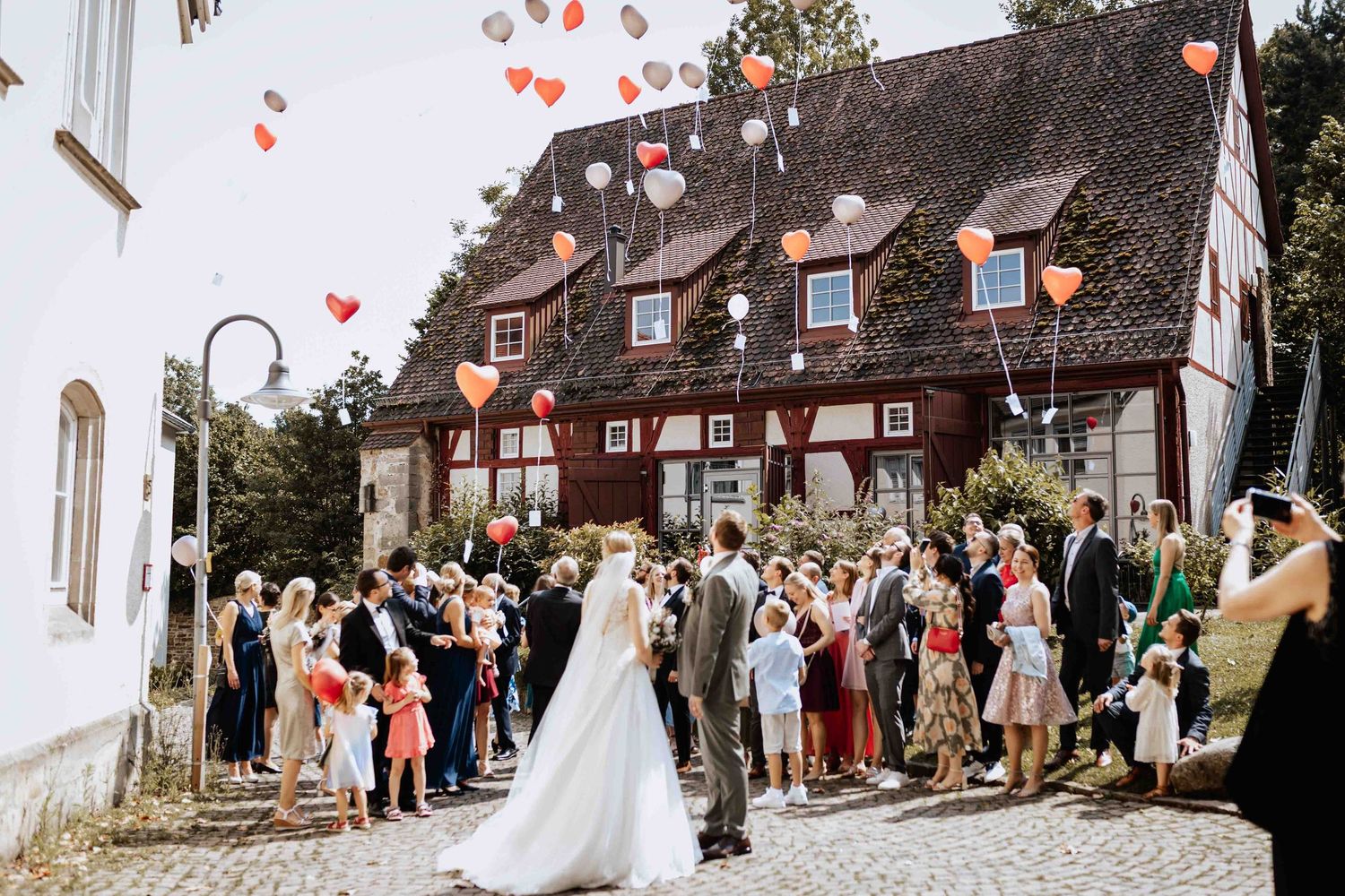 Brautpaar in Klosterhof in Denkendorf vor Klosterkirche, lassen Luftballons steigen