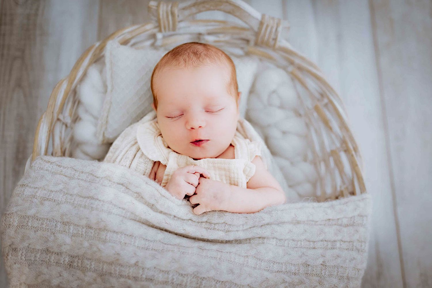 Baby schläft im Korb eingewickelt in einen wrap, natürlich im Studio fotografiert