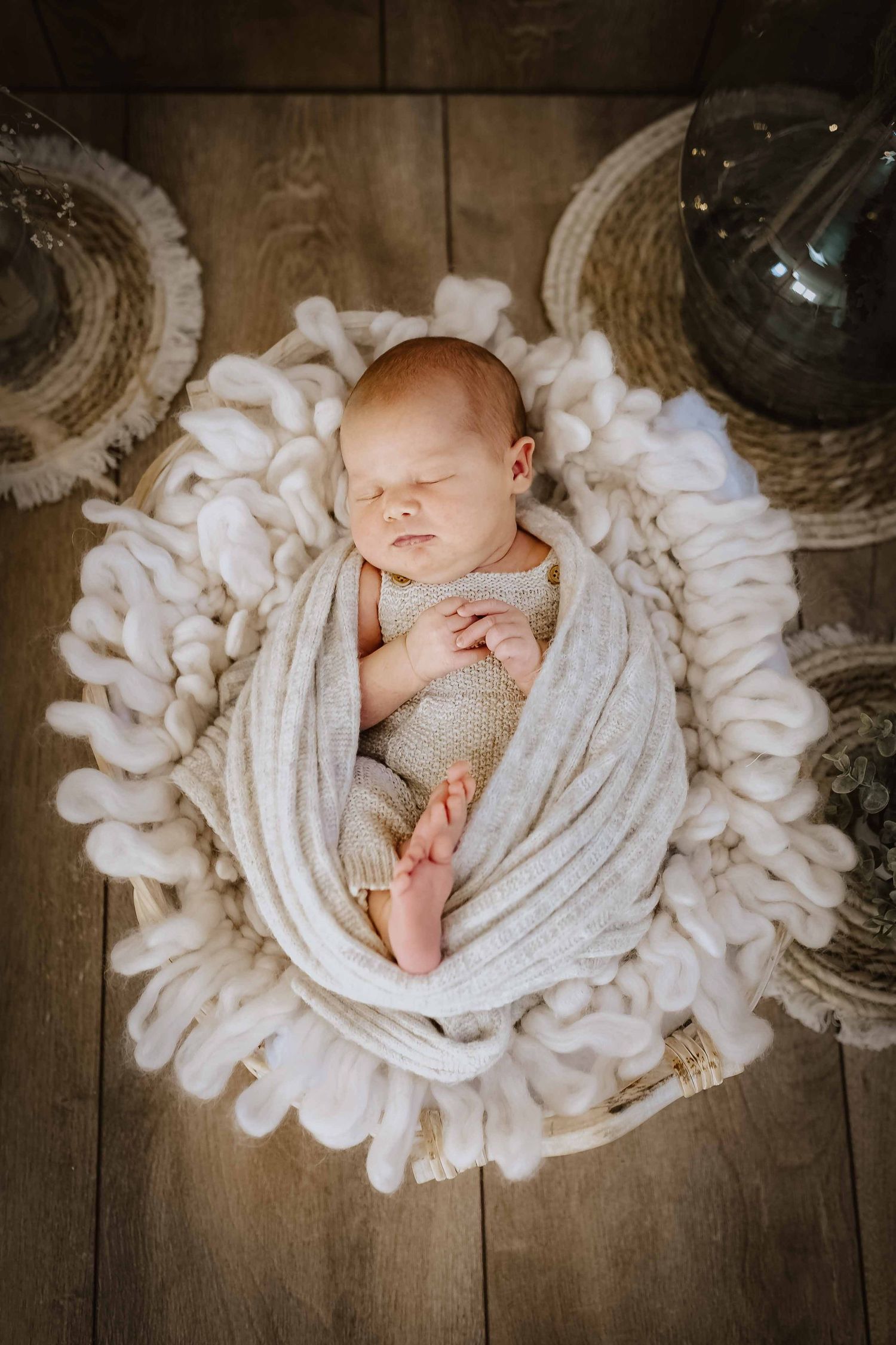 Baby schläft im Korb eingewickelt in einen wrap, natürlich im Studio fotografiert