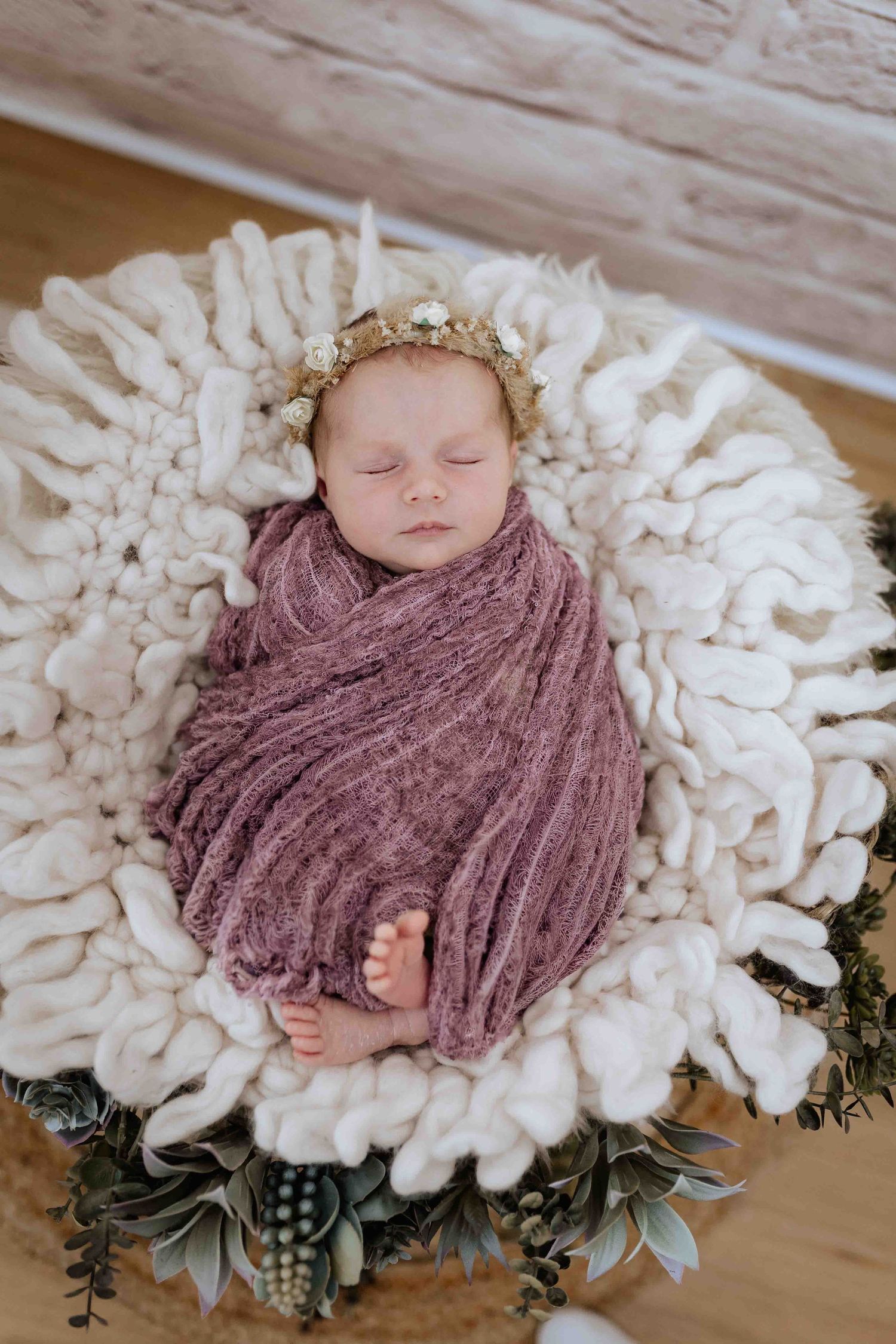 Baby schläft im Korb eingewickelt in einen wrap, natürlich im Studio fotografiert