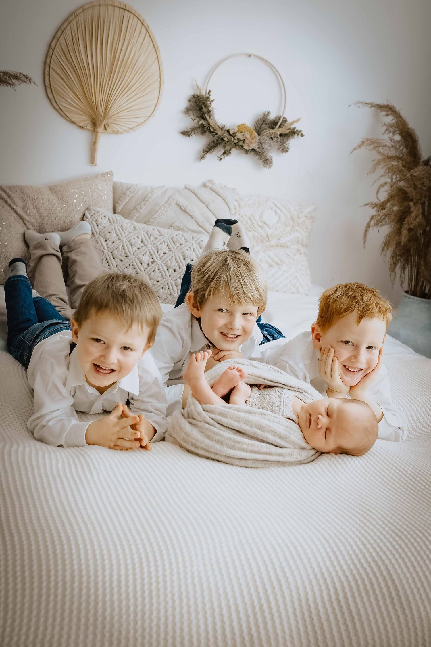 Geschwisterfoto im Studio mit schlafendem Baby eingepackt