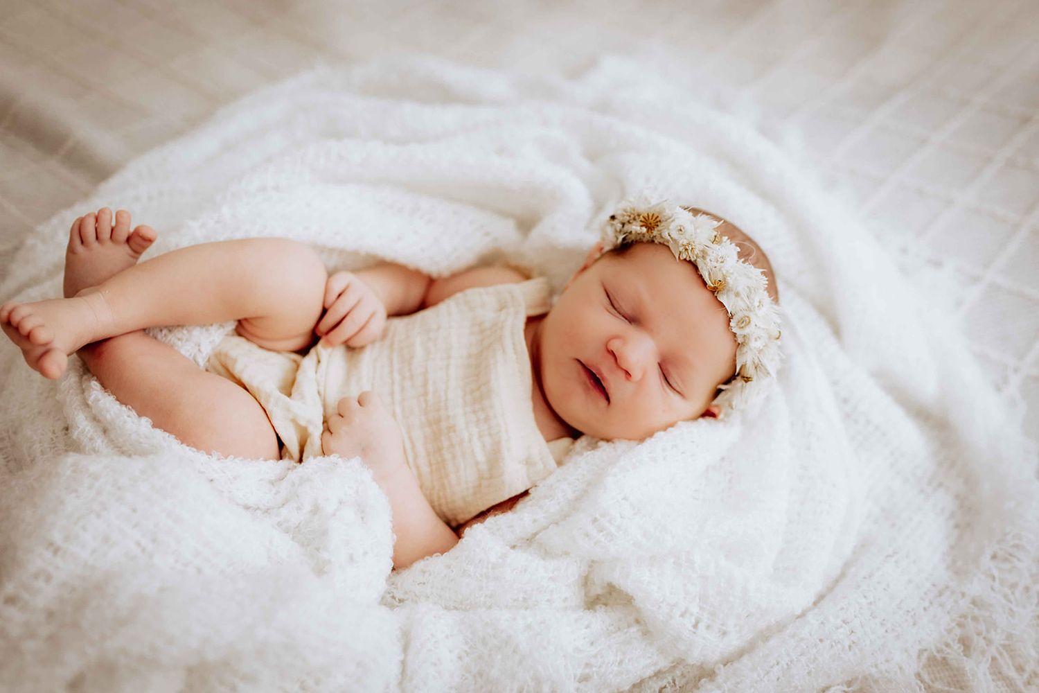 Baby liegt natürlich auf einer Decke mit Kranz auf dem Kopf und schläft