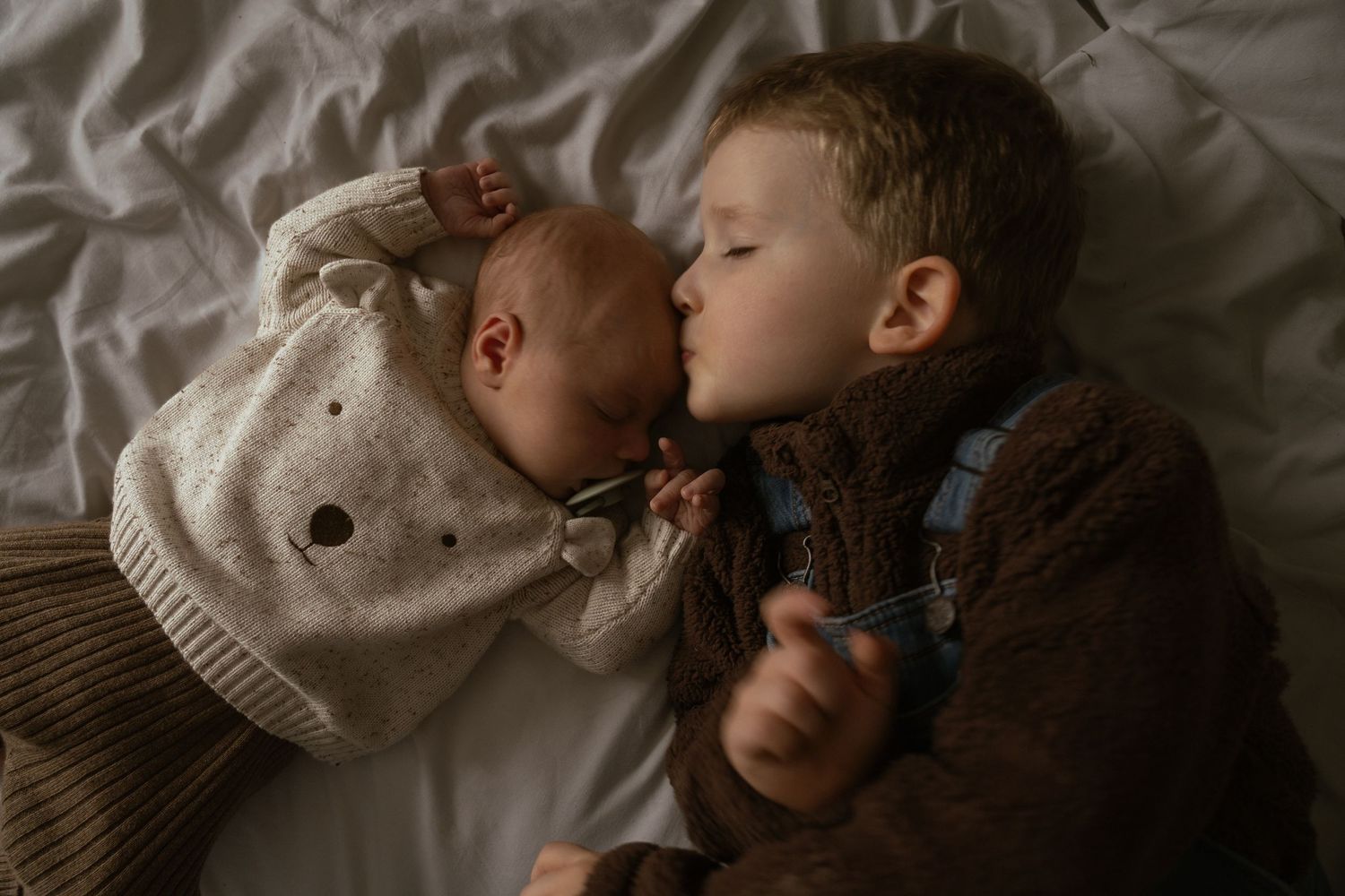 toddler kissing newborn baby