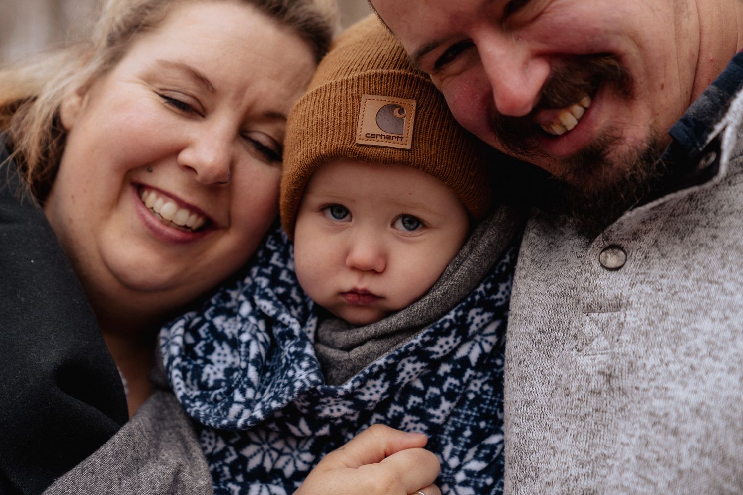 mom and dad cuddling toddler wrapped in blanket during outdoor photo session