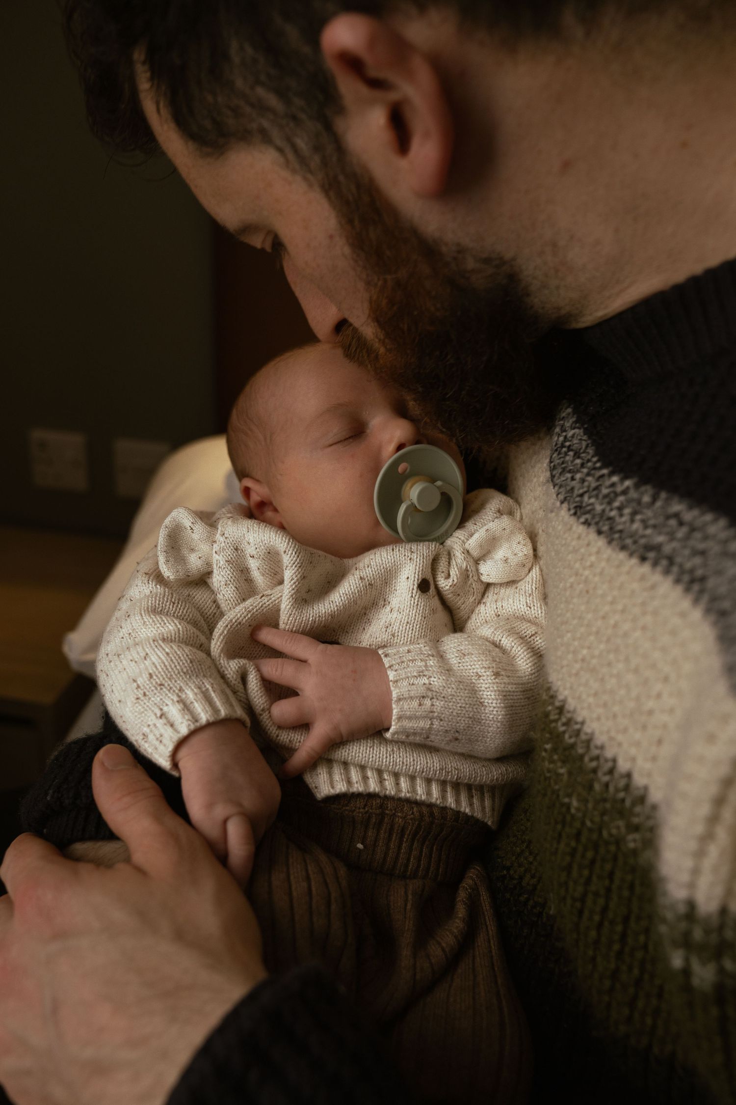Father kissing newborn baby during intimate lifestyle photo session