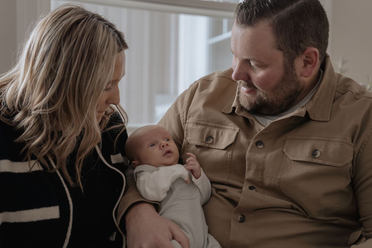 Parents holding newborn baby during cozy in-home lifestyle photo session