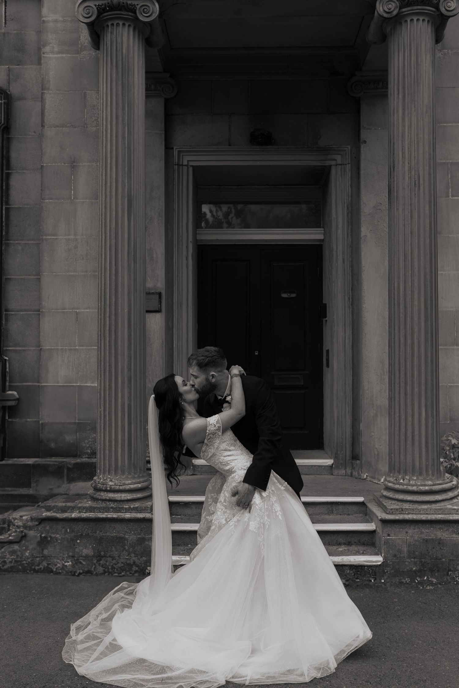 bride and groom kissing in front of building