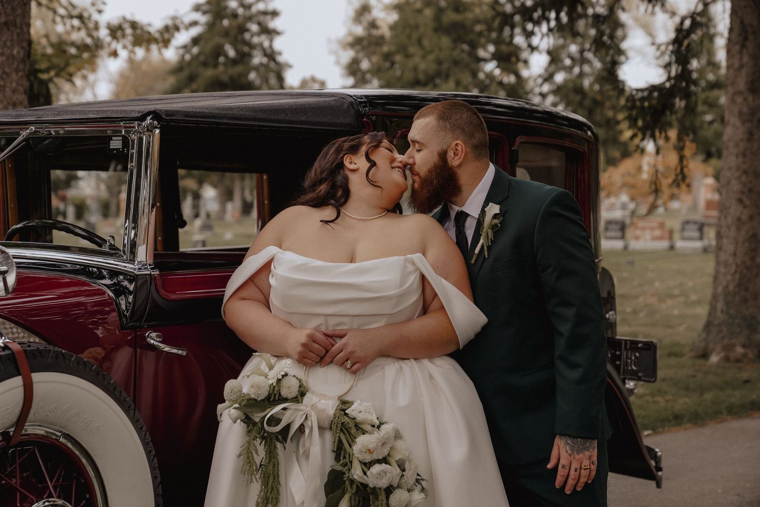 bride and groom kissing in front of old car