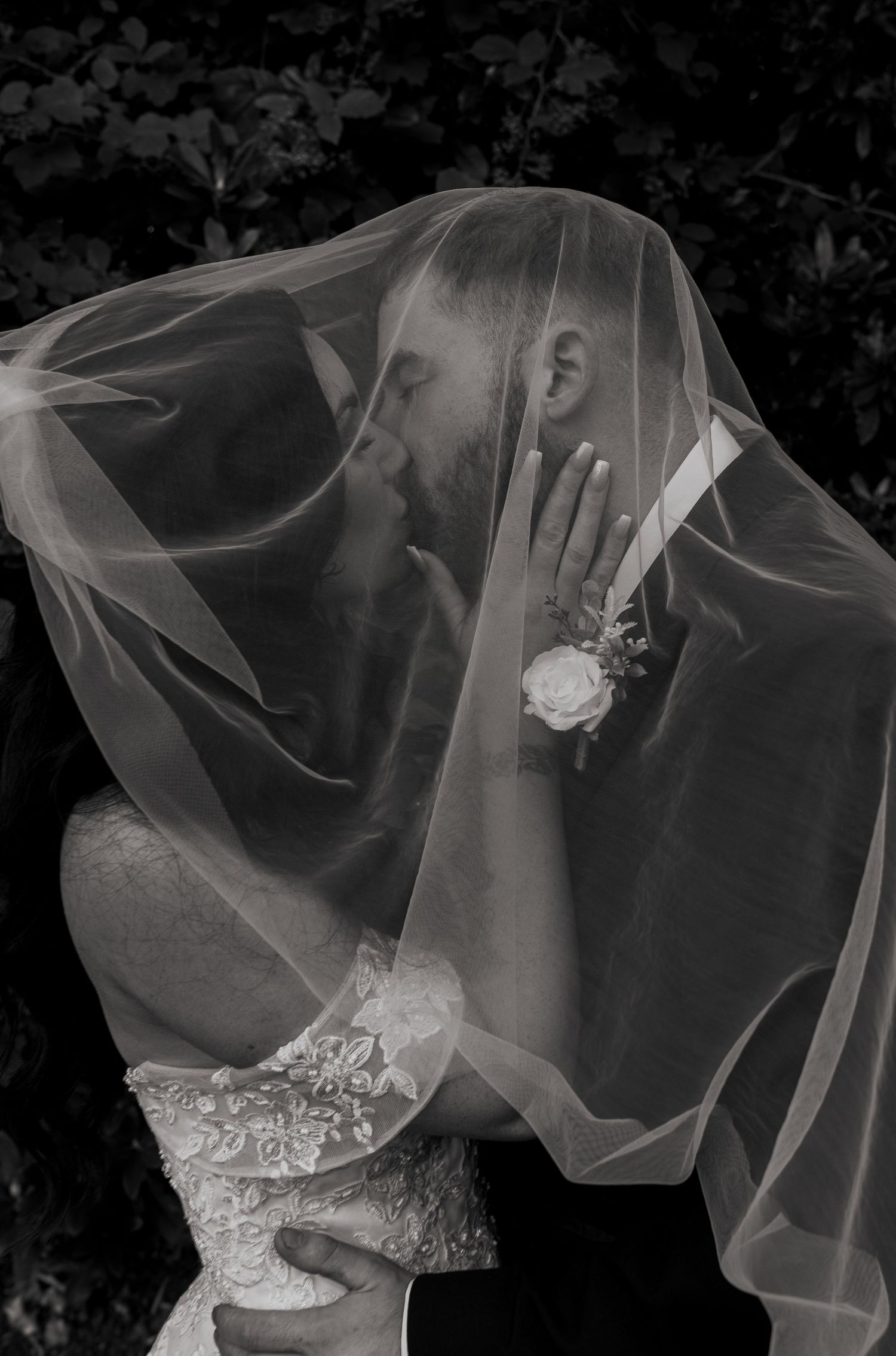 bride and groom under vail kissing