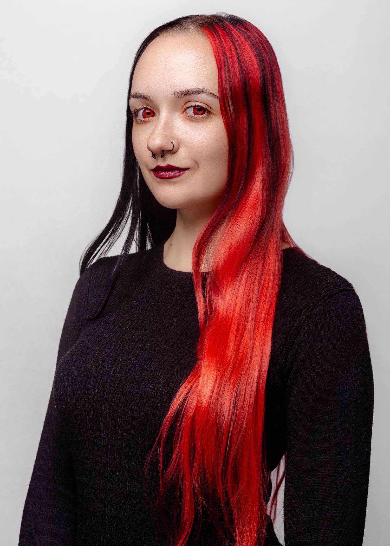 Series of fashion portraits showing model with vibrant red and black hair wearing black sweater against white backdrop.