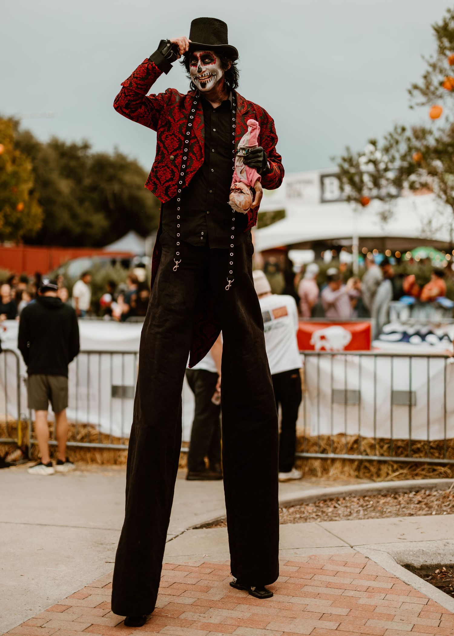 A vintage-inspired costume with black pants and red jacket creates a theatrical look on a brick pathway.