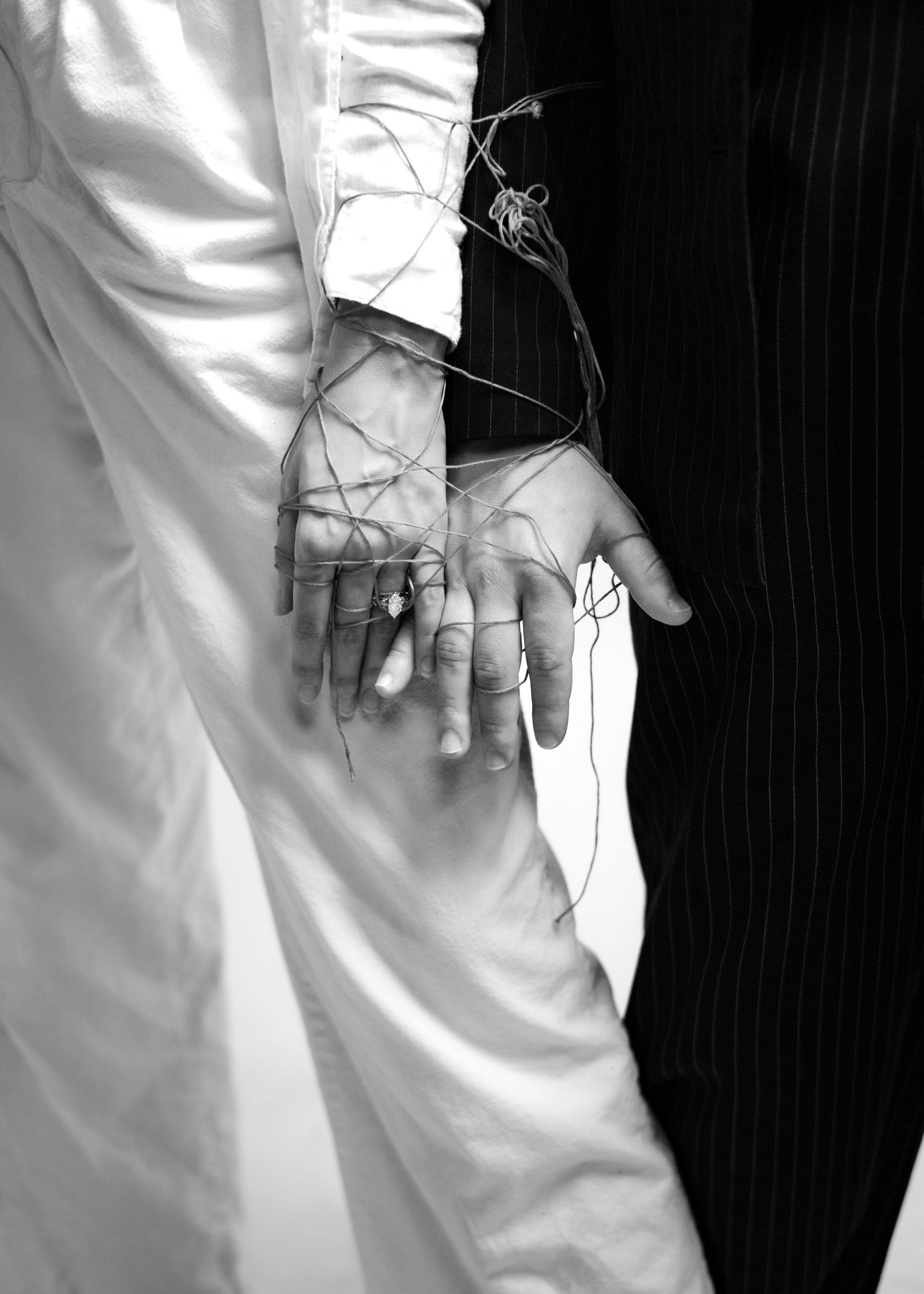 A close-up view of hands in white sleeves against a black background creating a repetitive pattern.