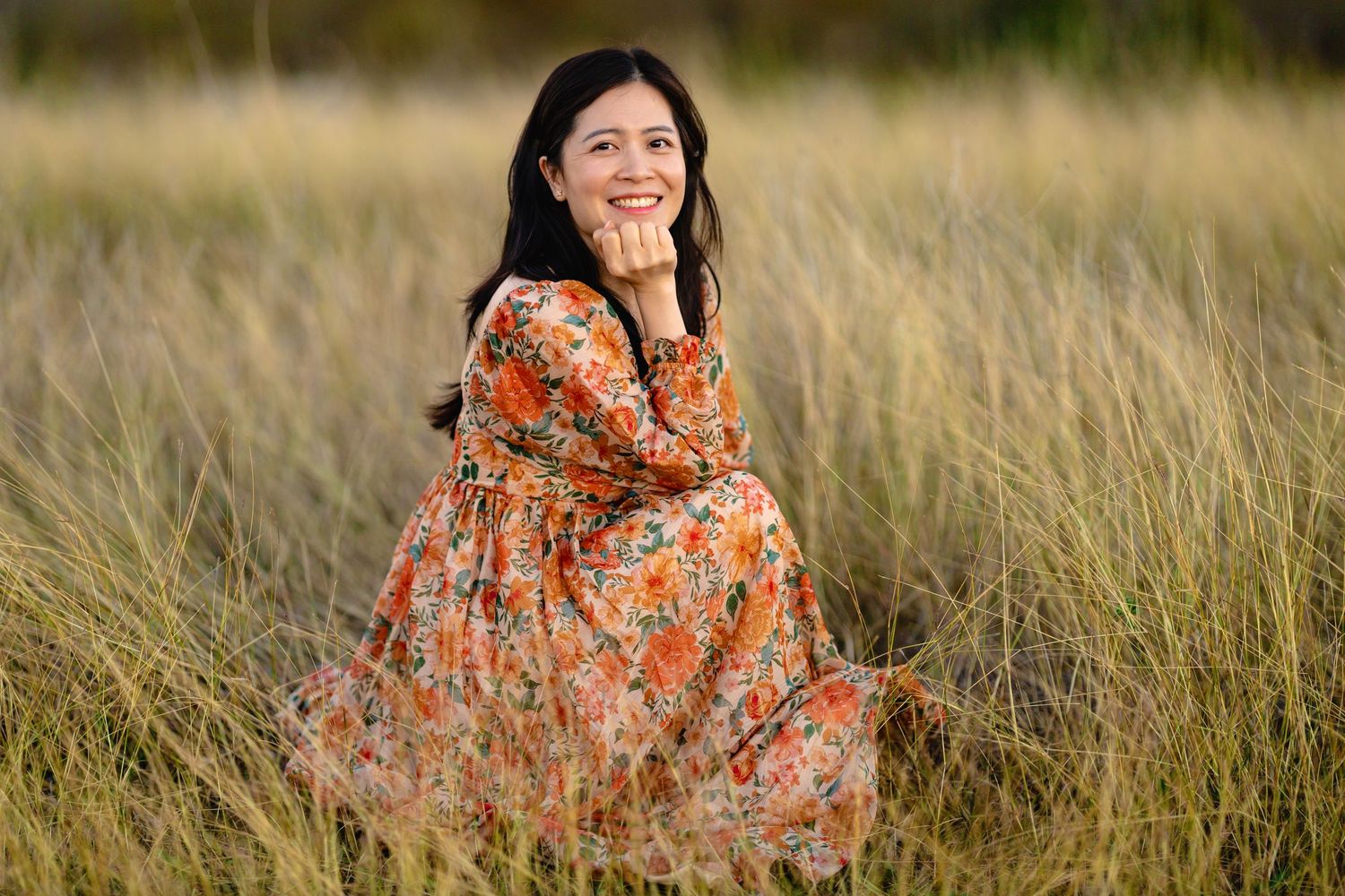 Candid shots of person wearing floral dress sitting in golden field during magic hour.