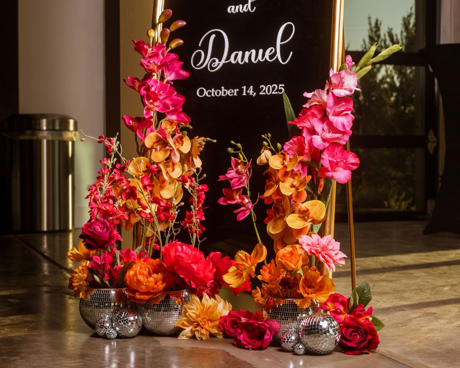 Vibrant floral arrangement with pink and orange blooms beside a wedding welcome sign for Daniel, October 14, 2025.