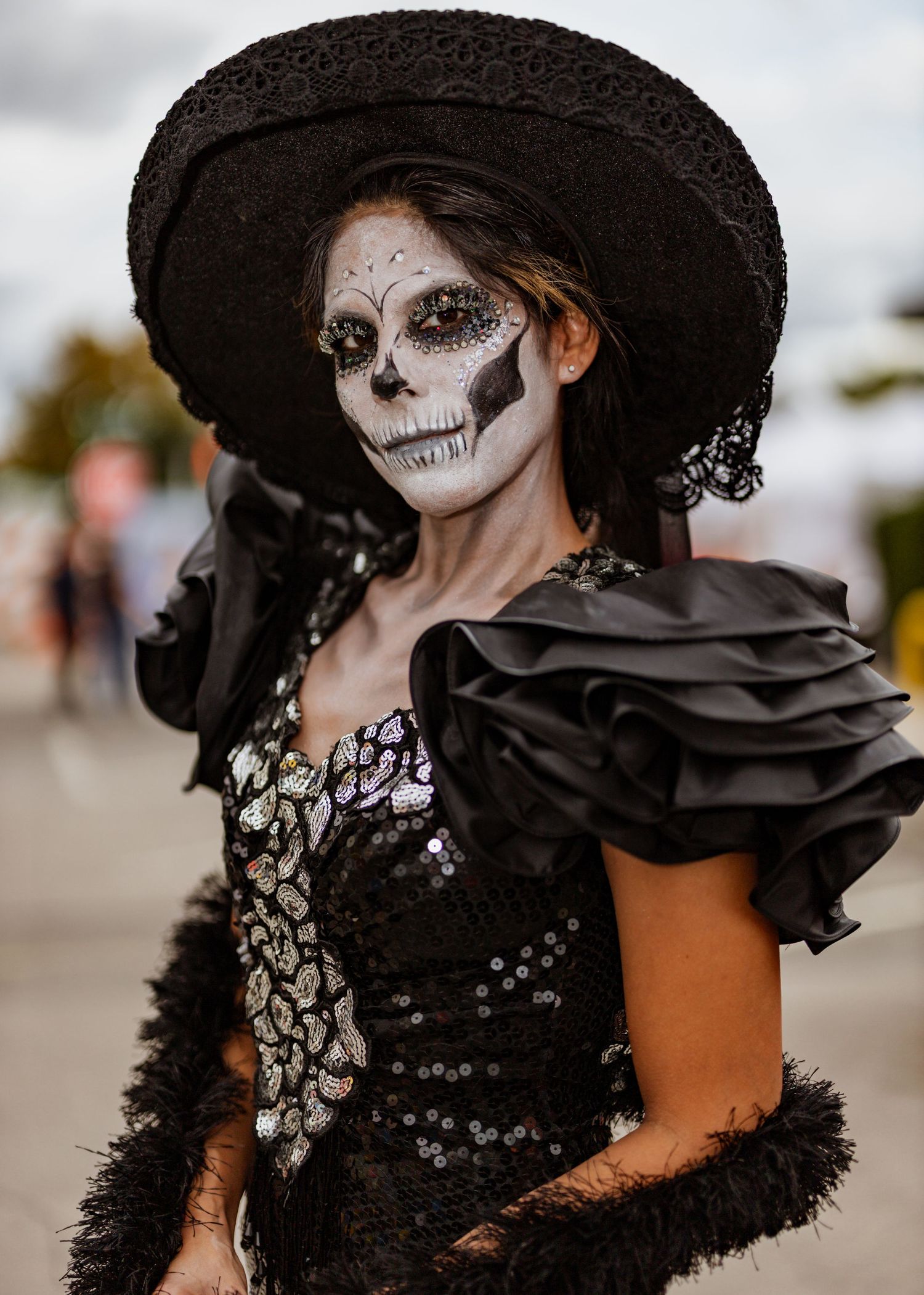 A gothic-style costume with black ruffled details and dramatic skeleton makeup under a wide-brimmed hat.
