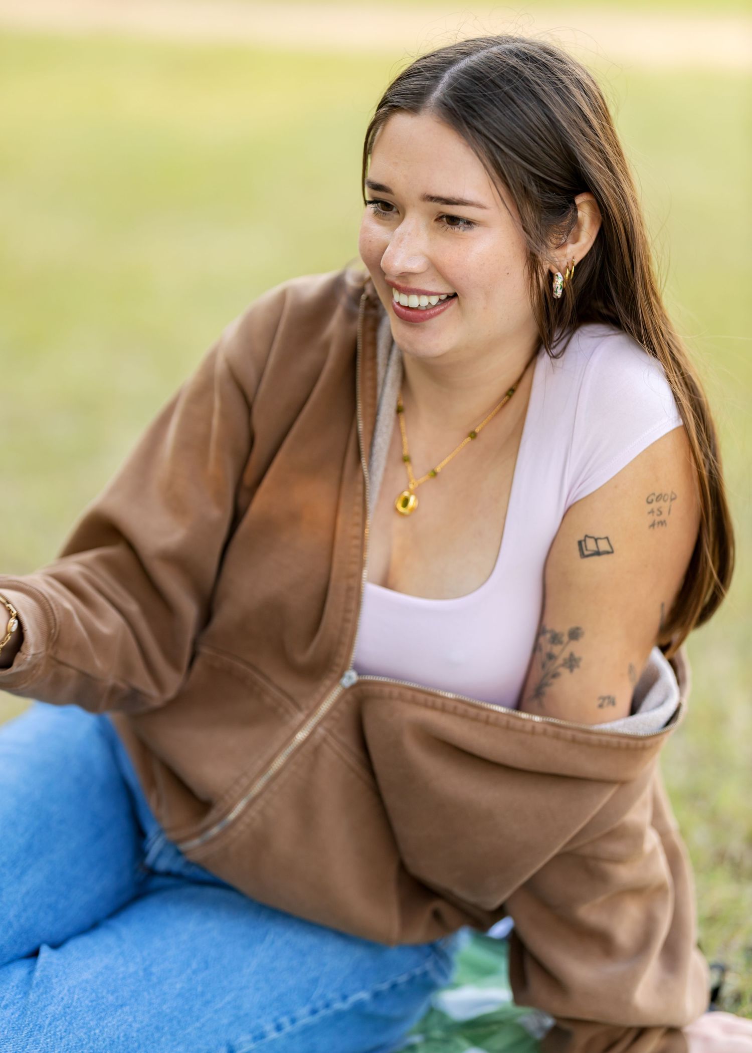 Person in brown jacket and white top lounging on blue blanket outdoors.