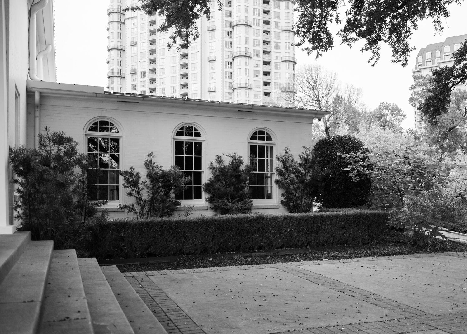 Black and white panoramic view of a stately mansion with white columns and landscaped grounds.