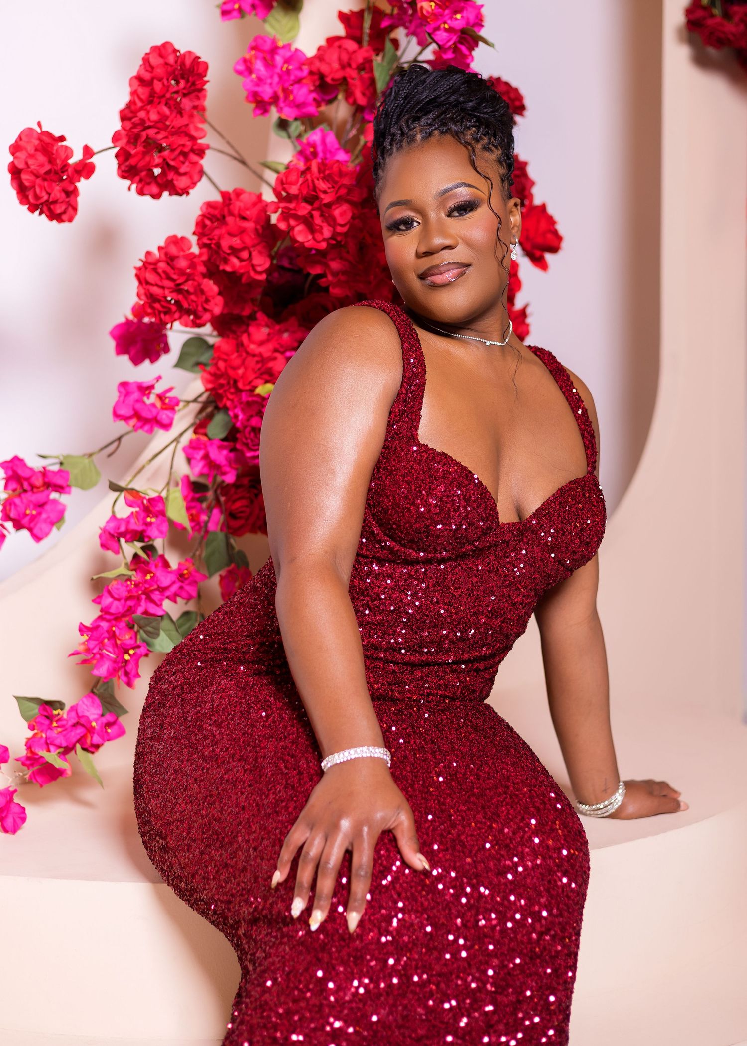 A stunning photoshoot featuring a sparkling burgundy sequin gown against a backdrop of vibrant pink bougainvillea flowers.