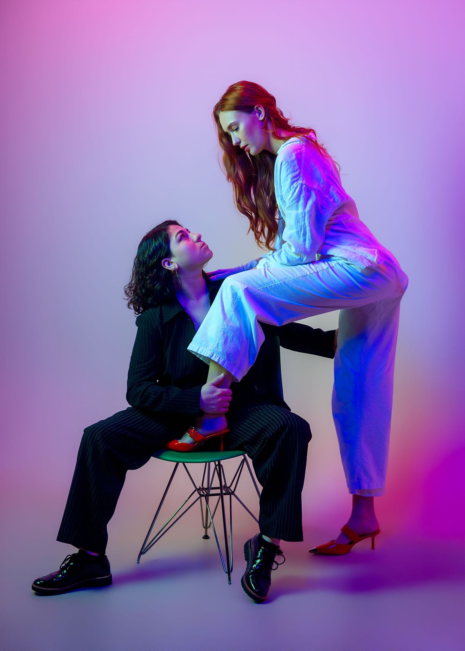 Artistic studio portraits with pink and purple lighting showing contrasting poses between figures.
