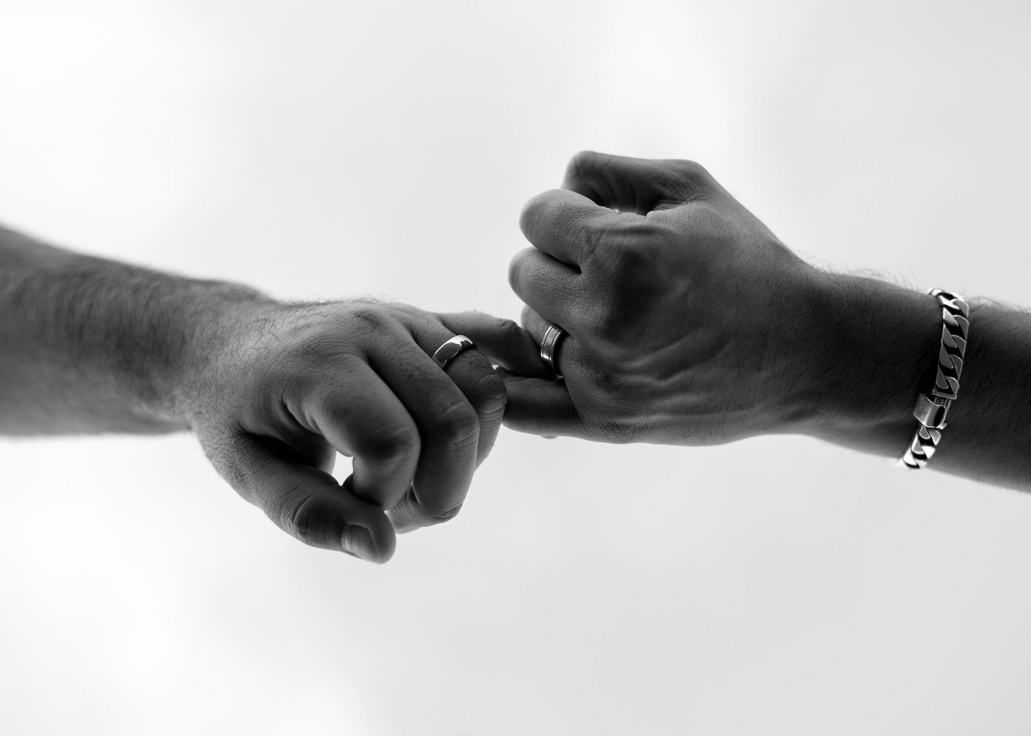 Two hands exchanging a ring in a black and white photo, symbolizing a proposal or wedding ceremony.