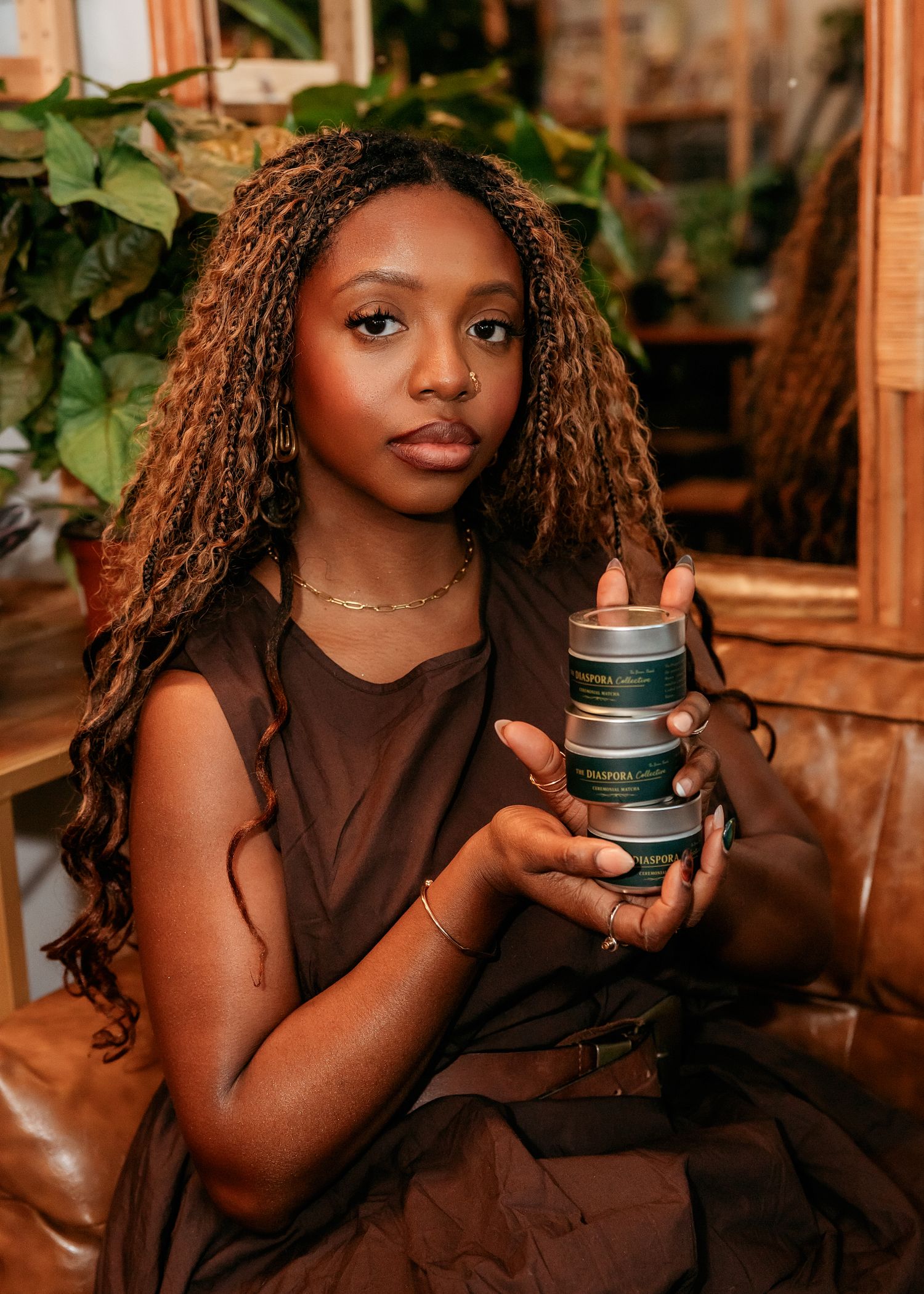 Person holding green product container while sitting in plant-filled space.