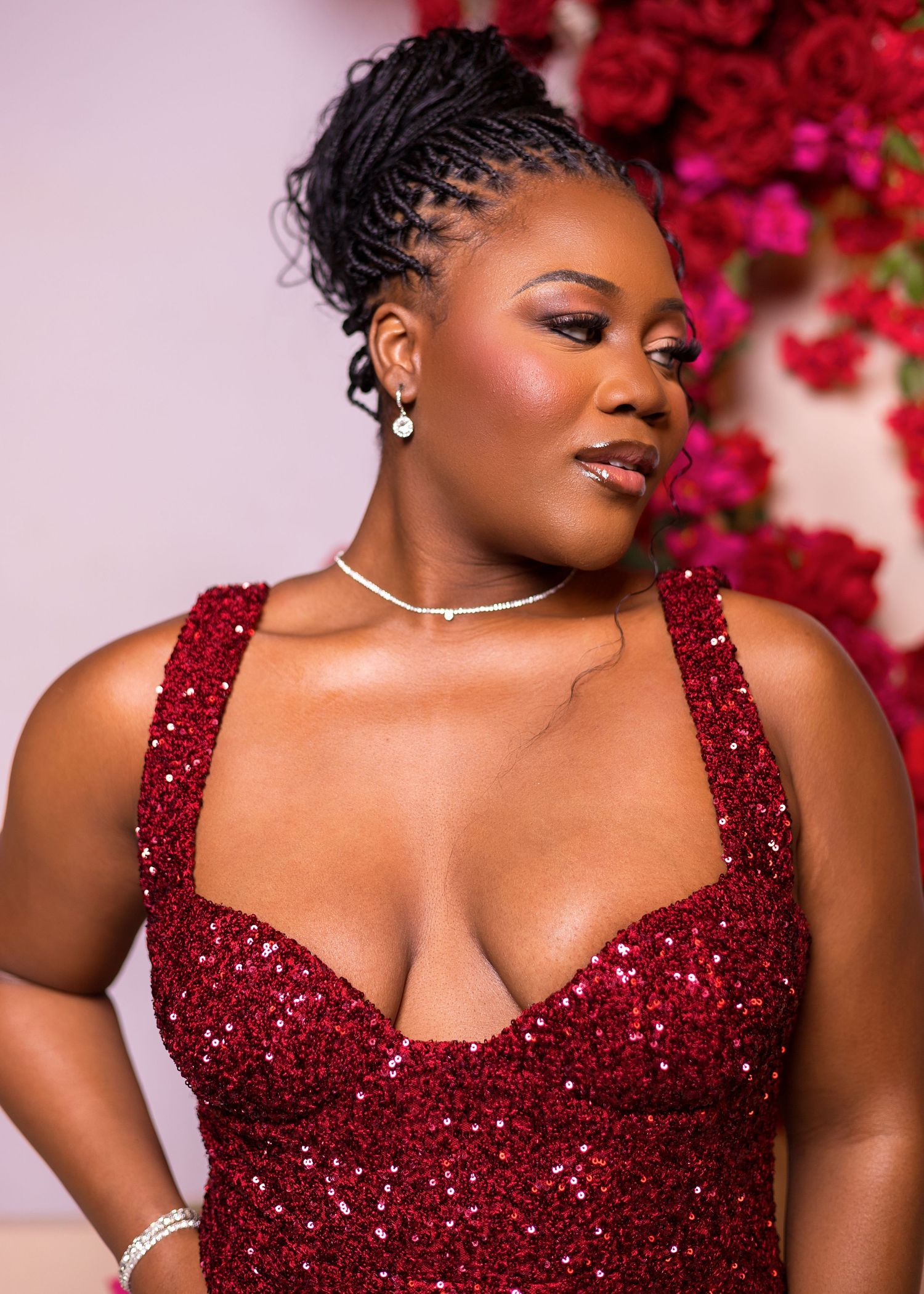 A sparkling burgundy sequined evening gown with sweetheart neckline against a floral backdrop.