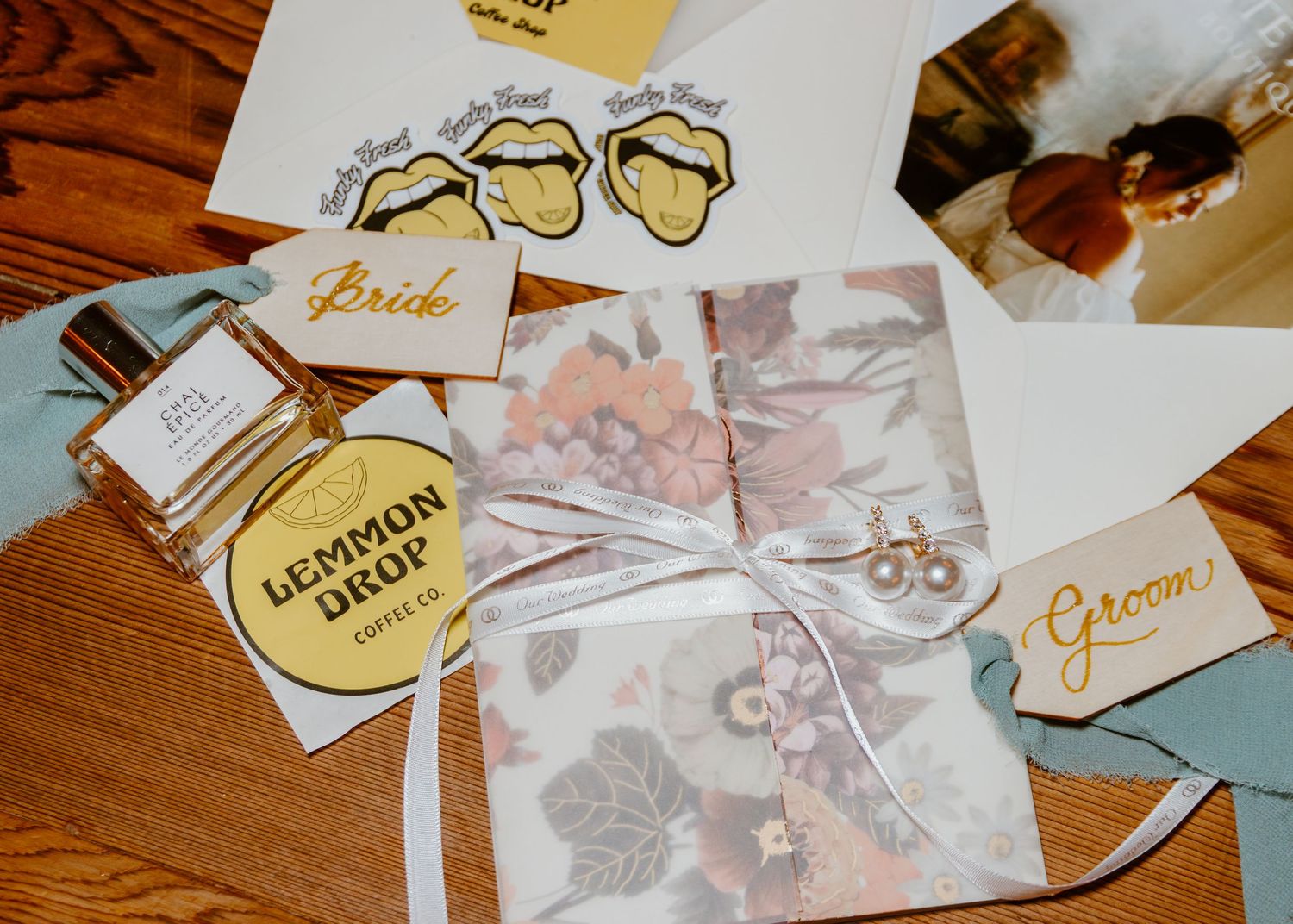 Wedding stationery and branded materials laid out on wooden surface.