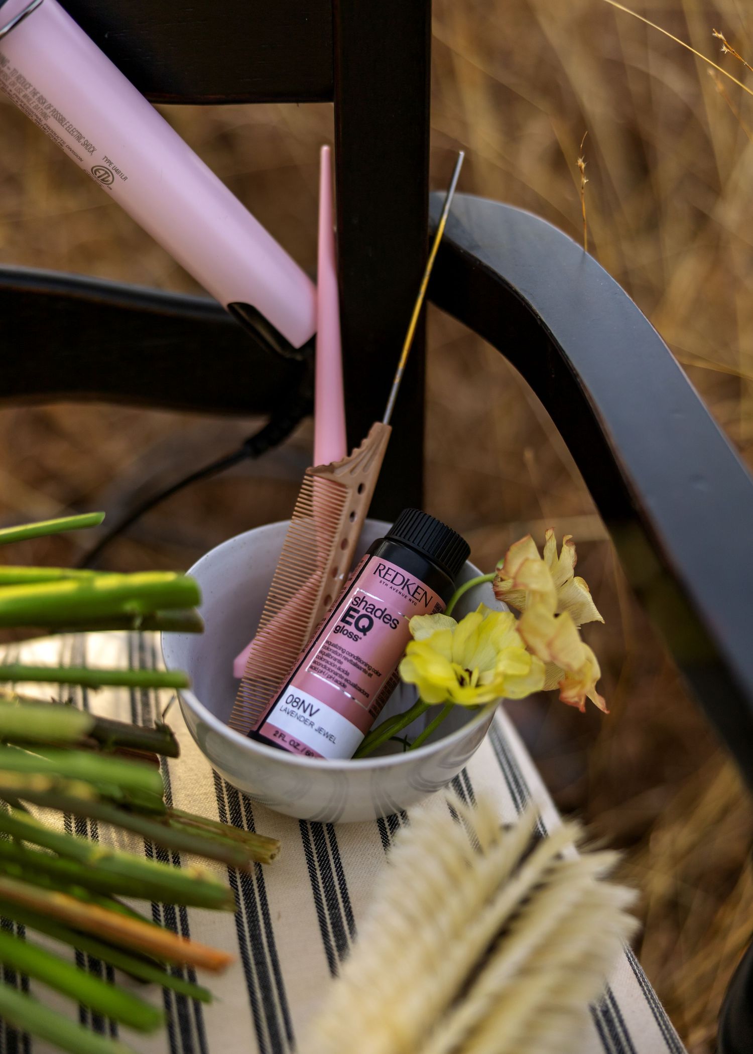Pink bottle and yellow daffodils arranged on striped fabric.