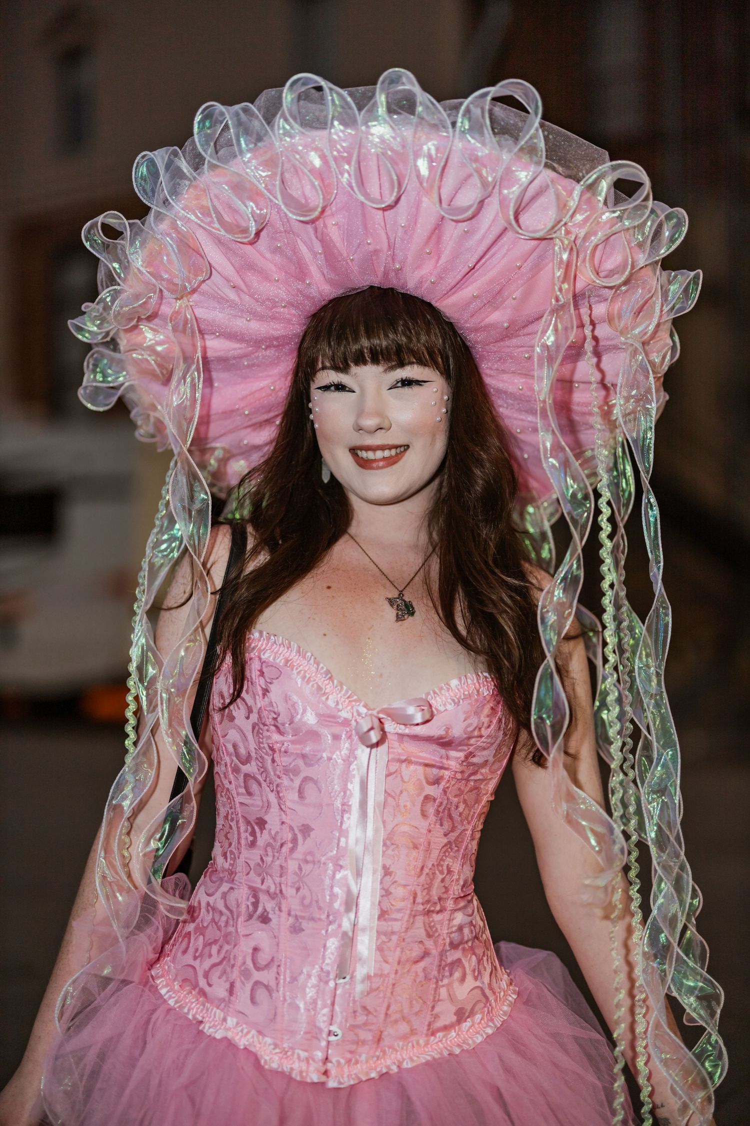 An elaborate pink princess costume with ruffled tulle headpiece and corset bodice creates a whimsical look.