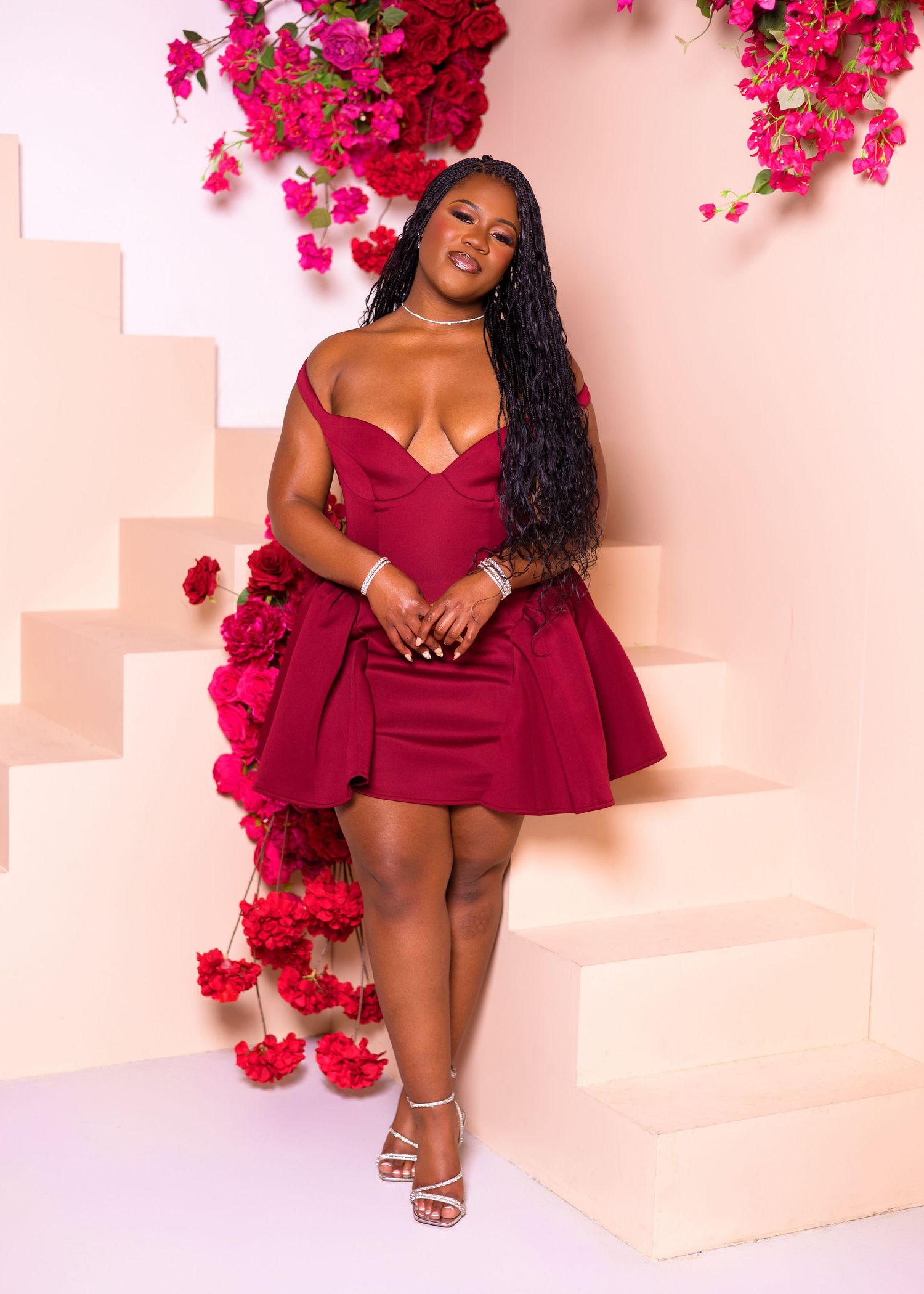 A red mini dress with ruffle details photographed in a romantic setting with pink and red floral decorations.