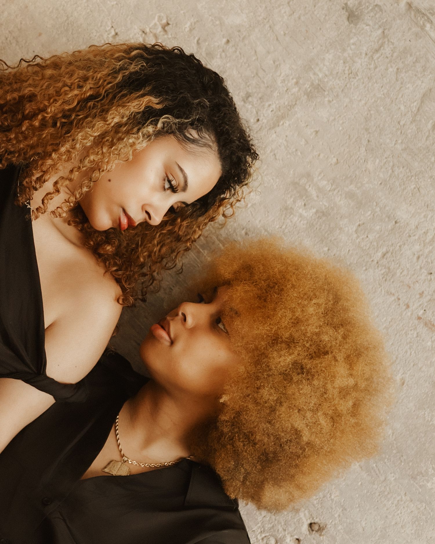 A series of artistic portrait photographs showing curly hair against a textured beige wall in warm earth tones.