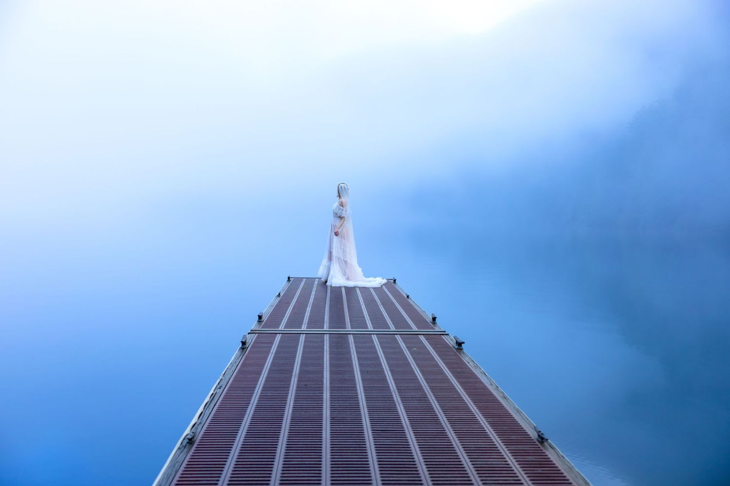 Looking up at the Empire State Building spire reaching into a dramatic blue cloudy sky.