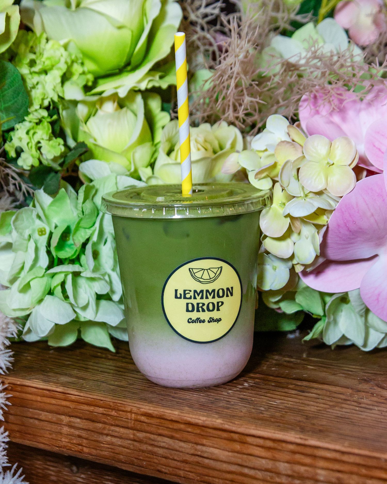 Green cocktail glasses displayed among pink and white hydrangea flower arrangements.