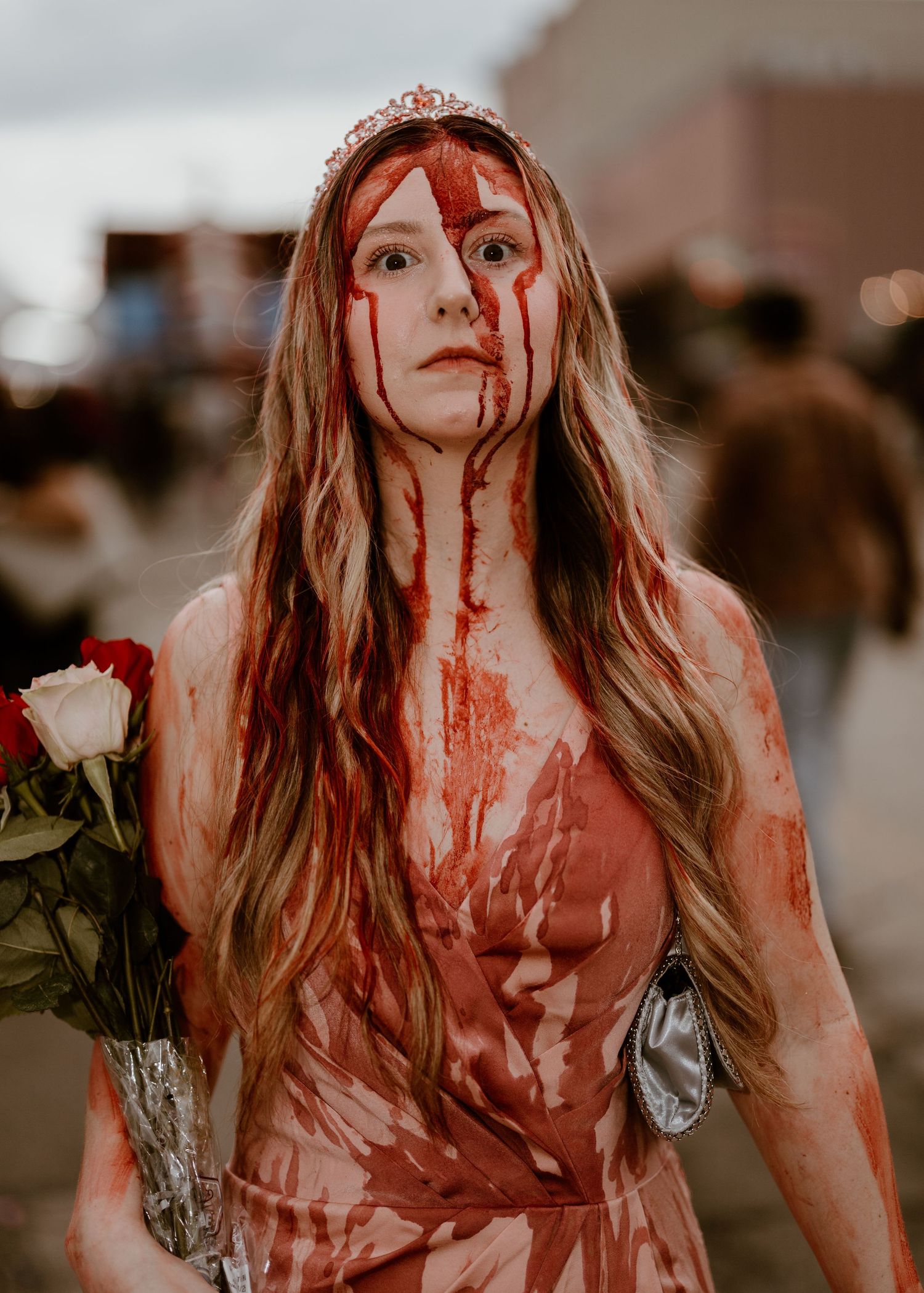A Halloween-themed portrait featuring long blonde hair, a tiara, and dramatic fake blood effects with a white rose.